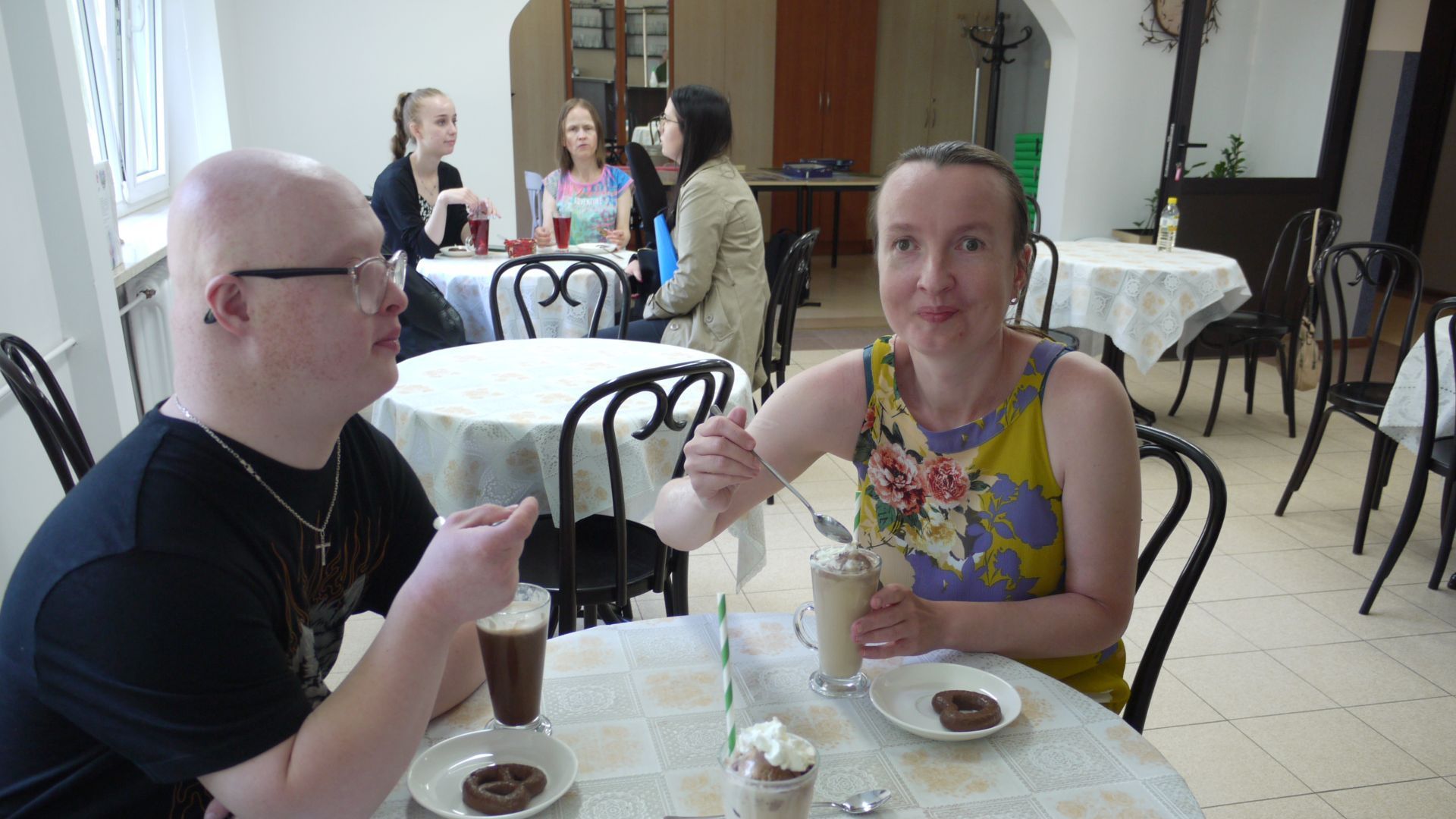 Uczestnicy siedzący przy stoliku z kawą i gorącą czekoladą.