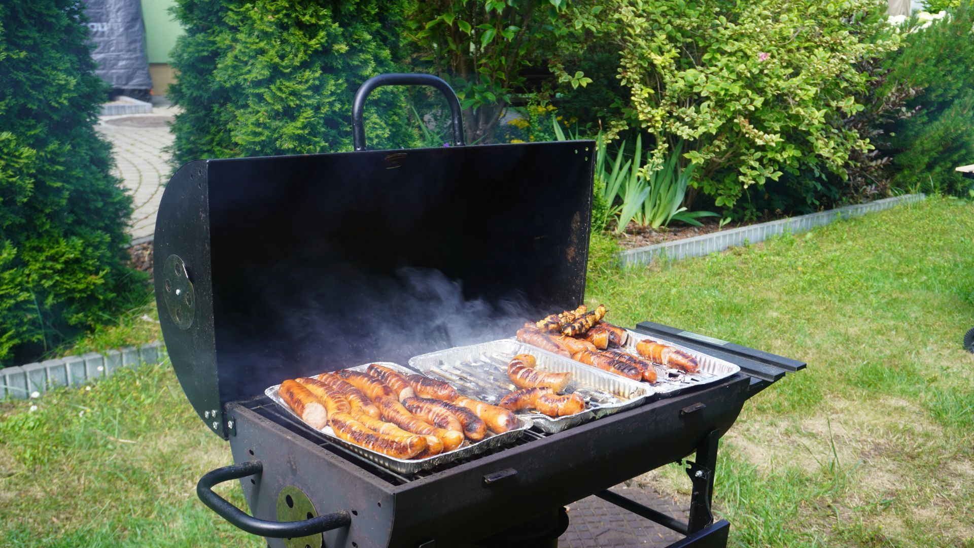 Kiełbaski piekące się na grillu.