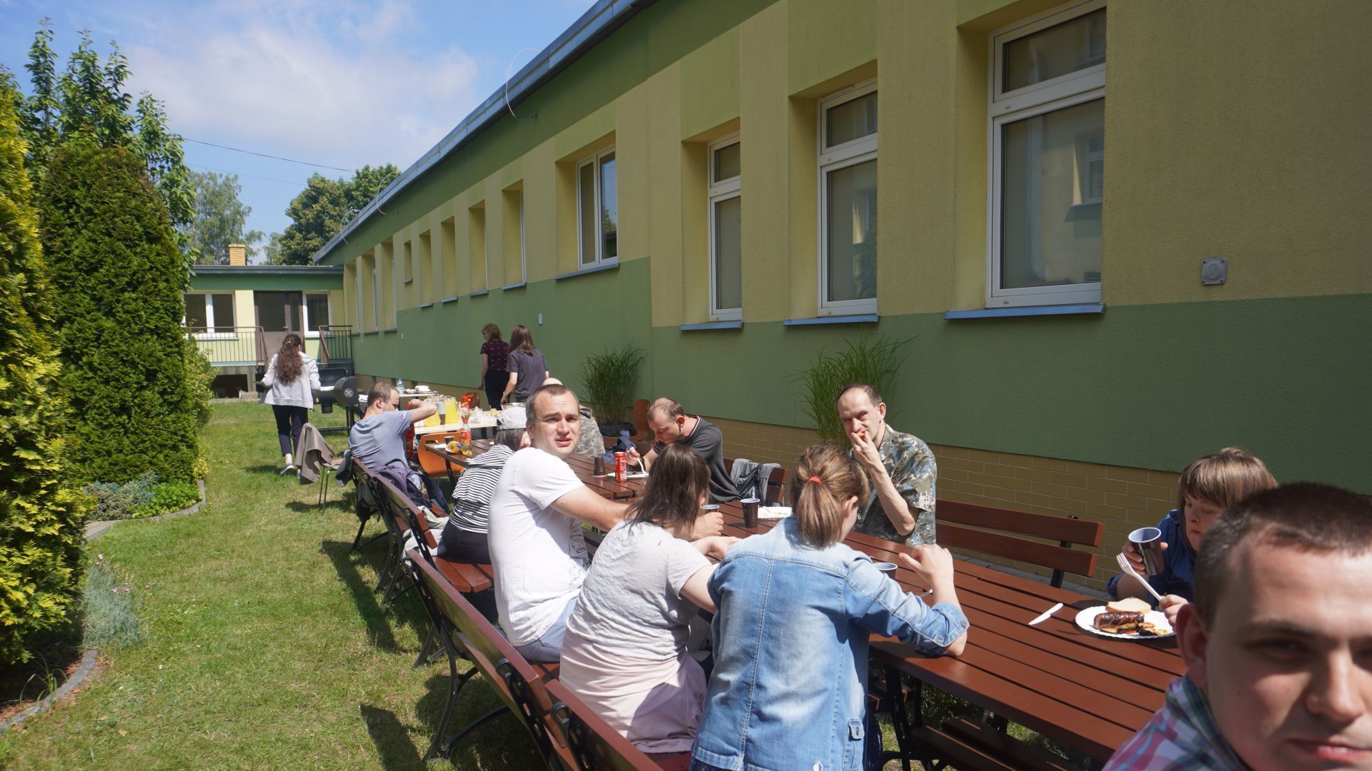 Uczestnicy siedzą przy stołach podczas grilla.