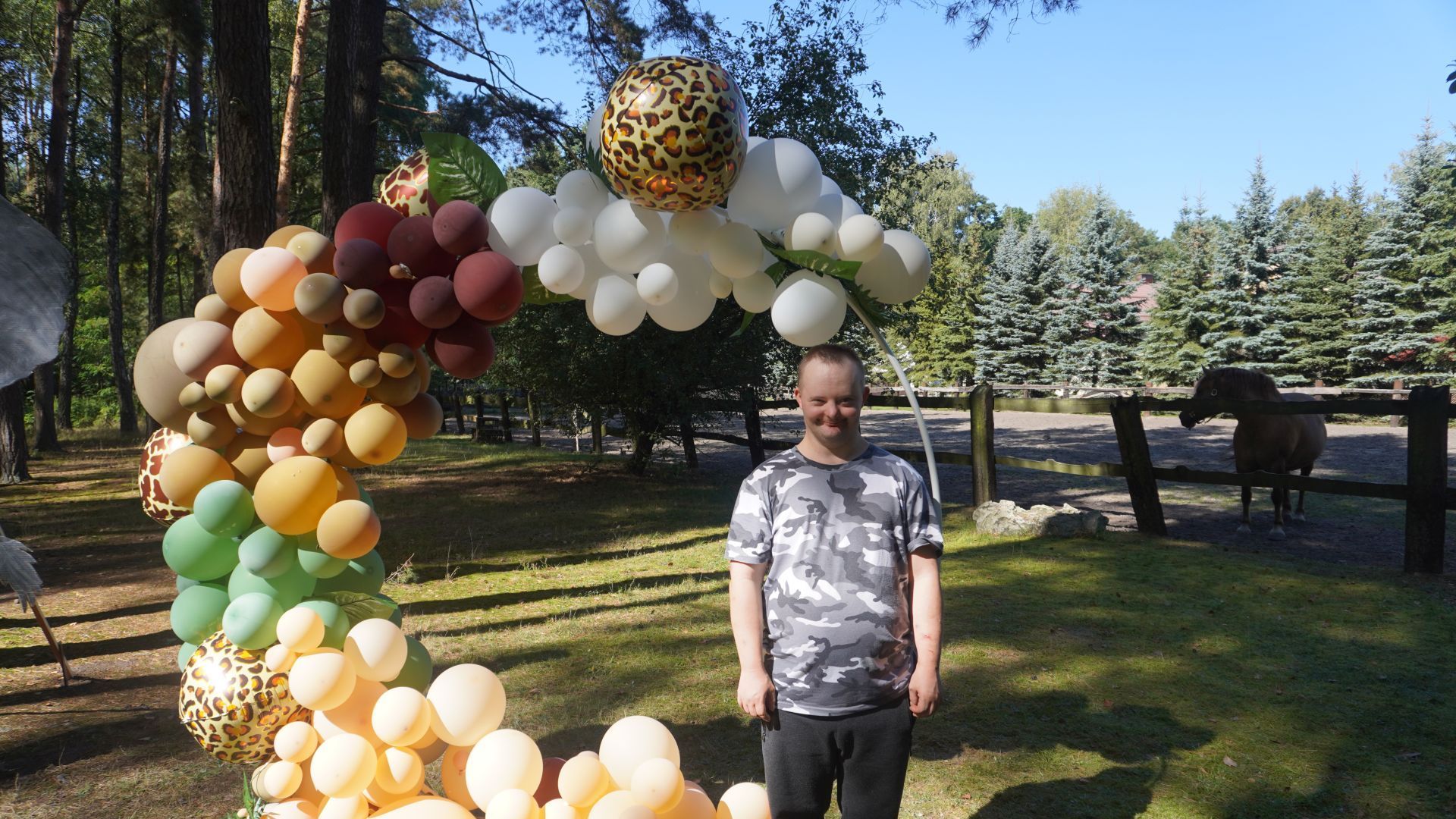 Uczestnik pozuje do zdjęcia na tle kolorowych balonów.