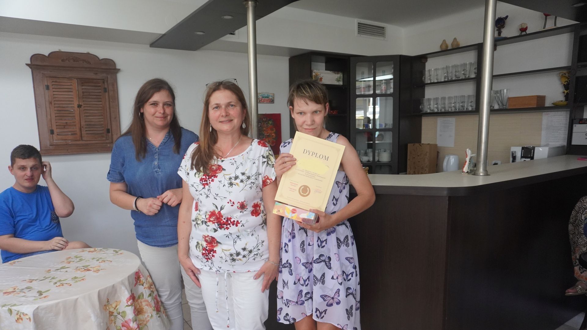 Uczestniczka wraz z terapeutkami pozuje do zdjęcia z dyplomem za zajęcie I miejsca w turnieju piłkarzyków stołowych.
