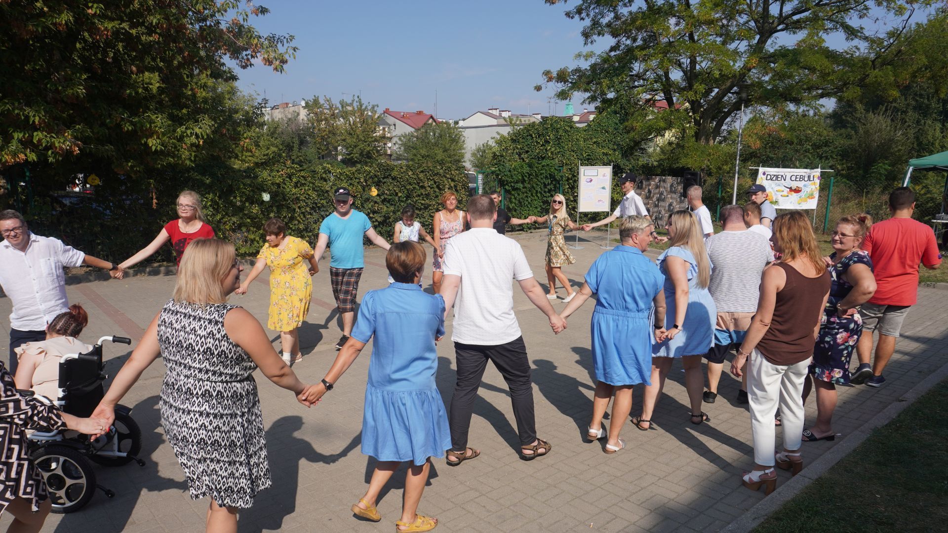 Uczestnicy imprezy ''Dzień Cebuli'' tańczą w kółku trzymając się za ręce.