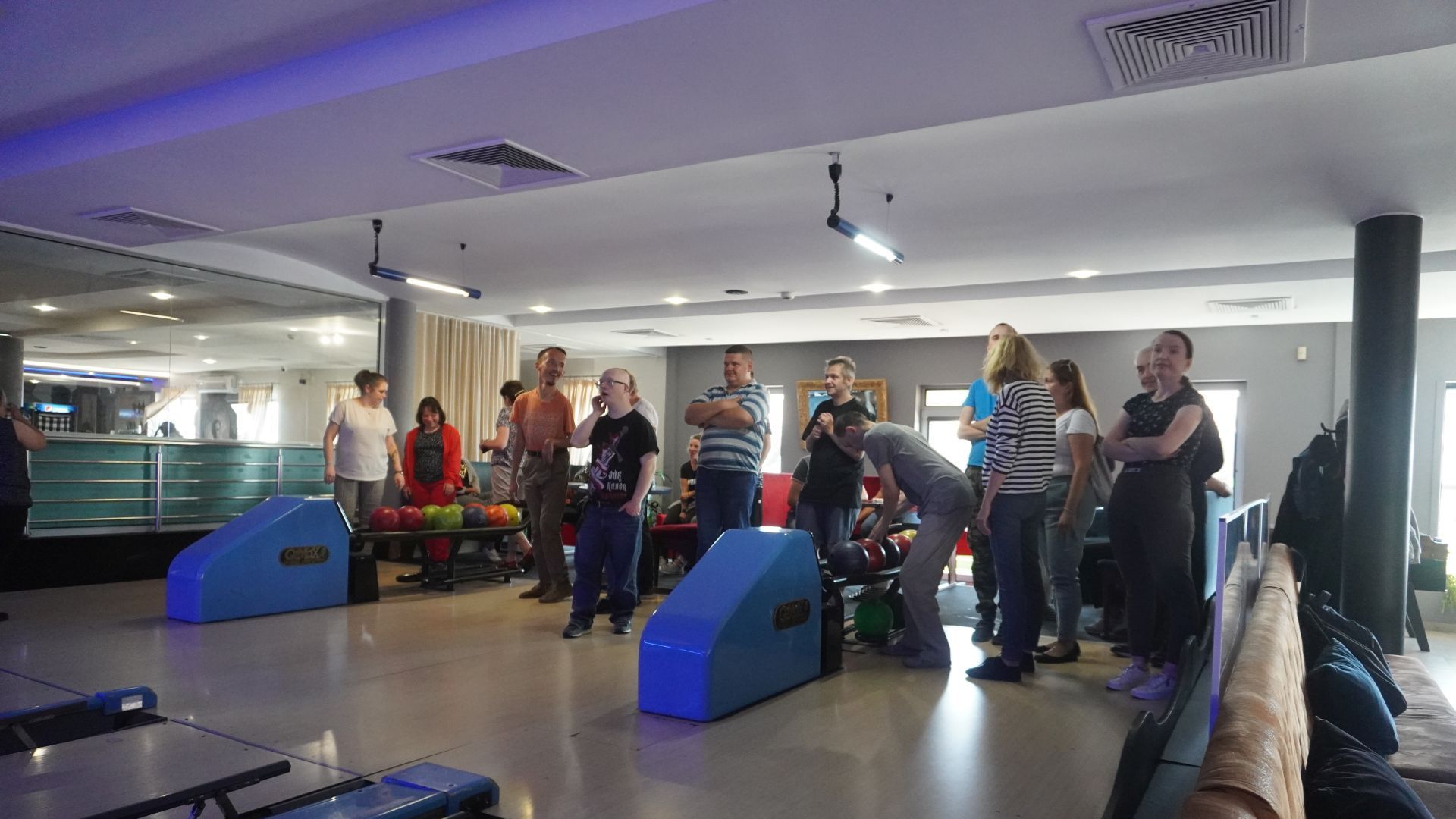 Uczestnicy stoją przy torach do gry w kręgle.