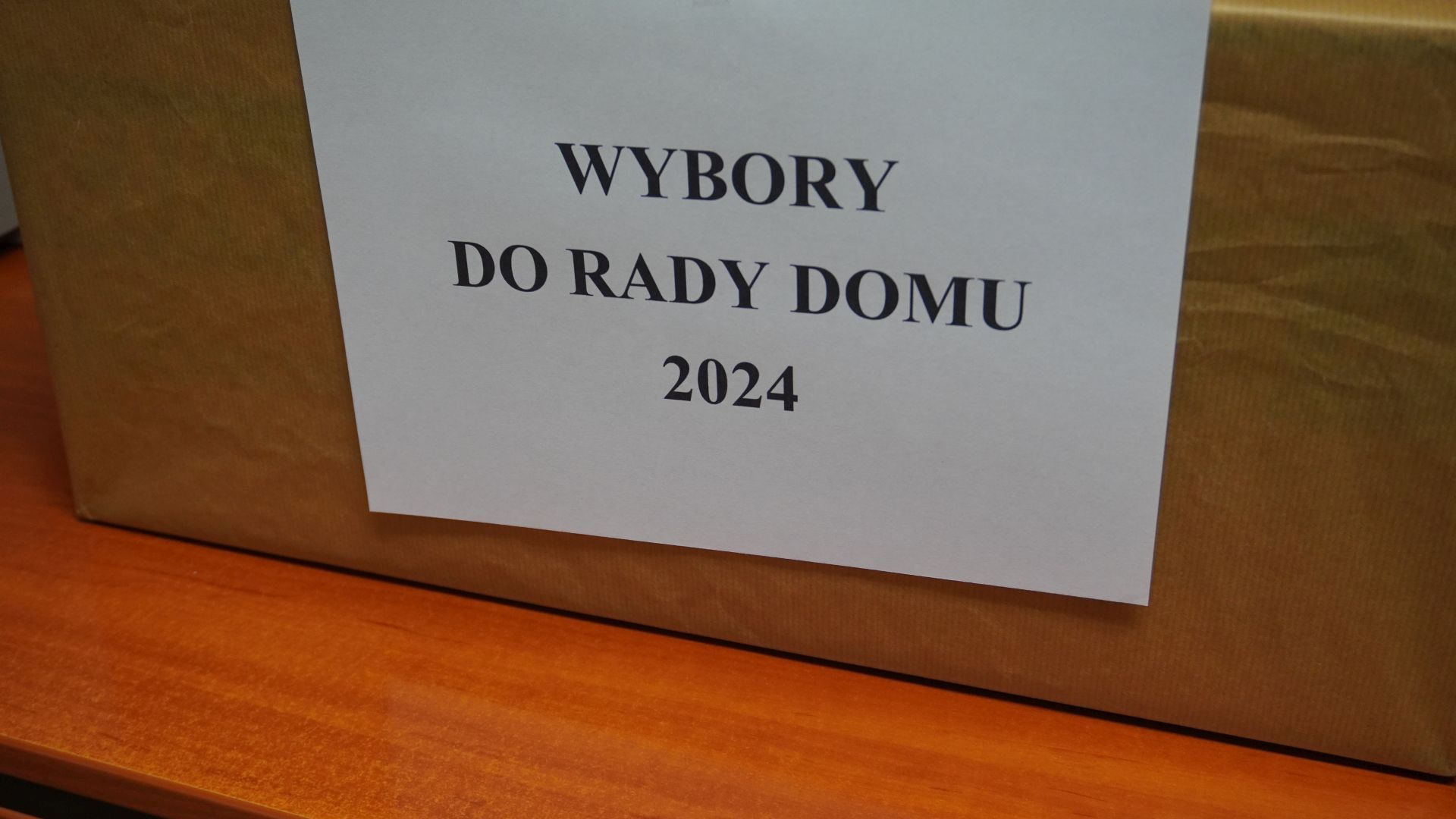 Kartka na urnie wyborczej z napisem wybory do Rady Domu 2024.