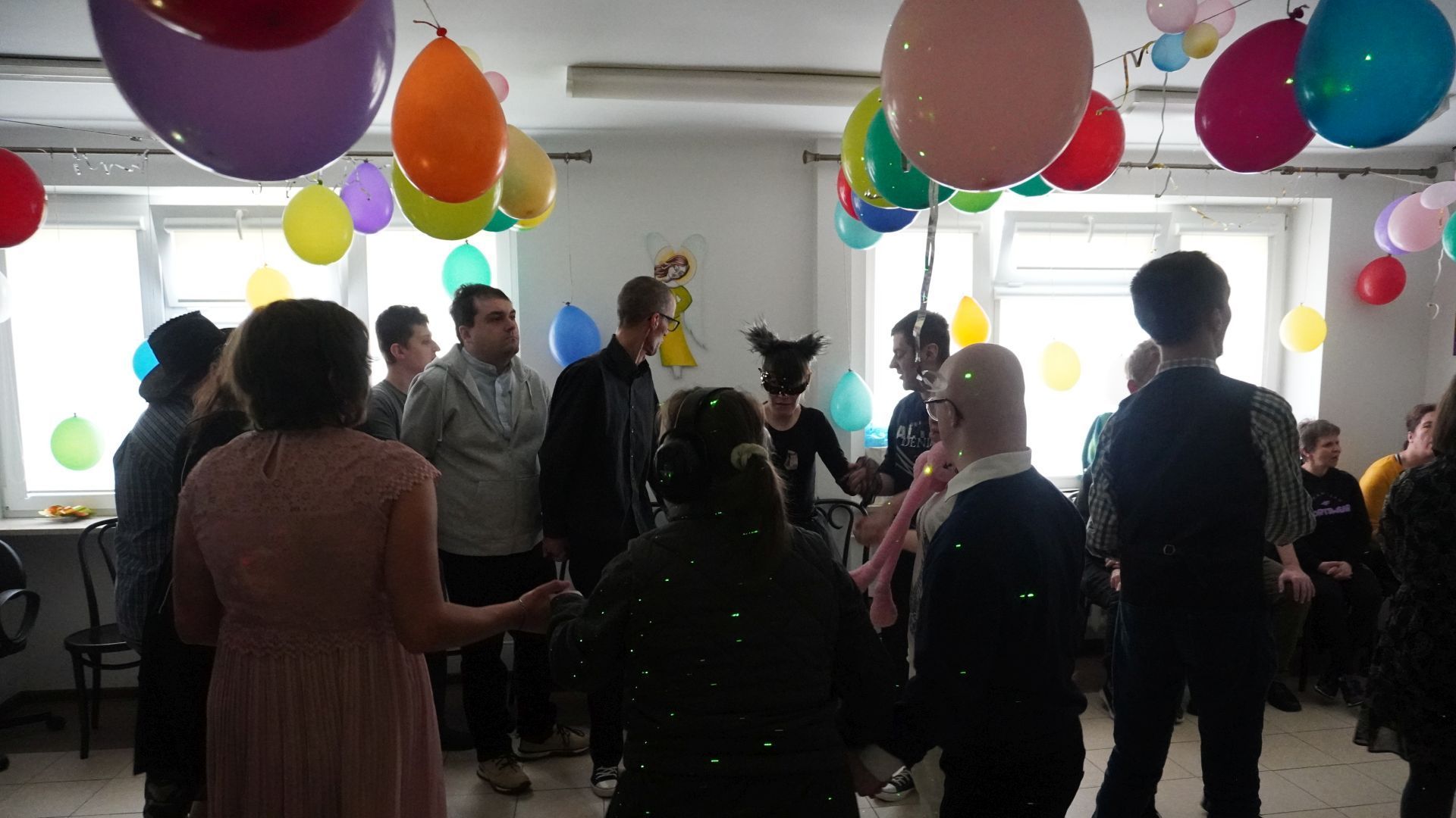 Uczestnicy tańczą w kółku trzymając się za ręce. 