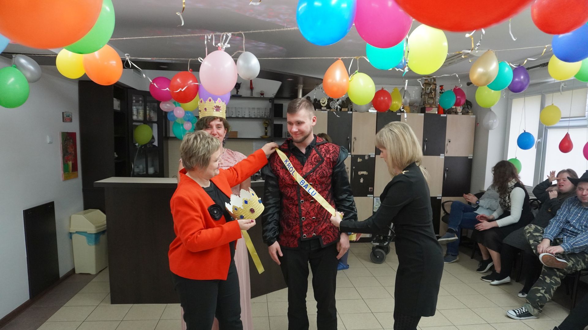 Pani dyrektor Justyna Juszczak wraz z terapeutką zakładają szarfę królowi balu.