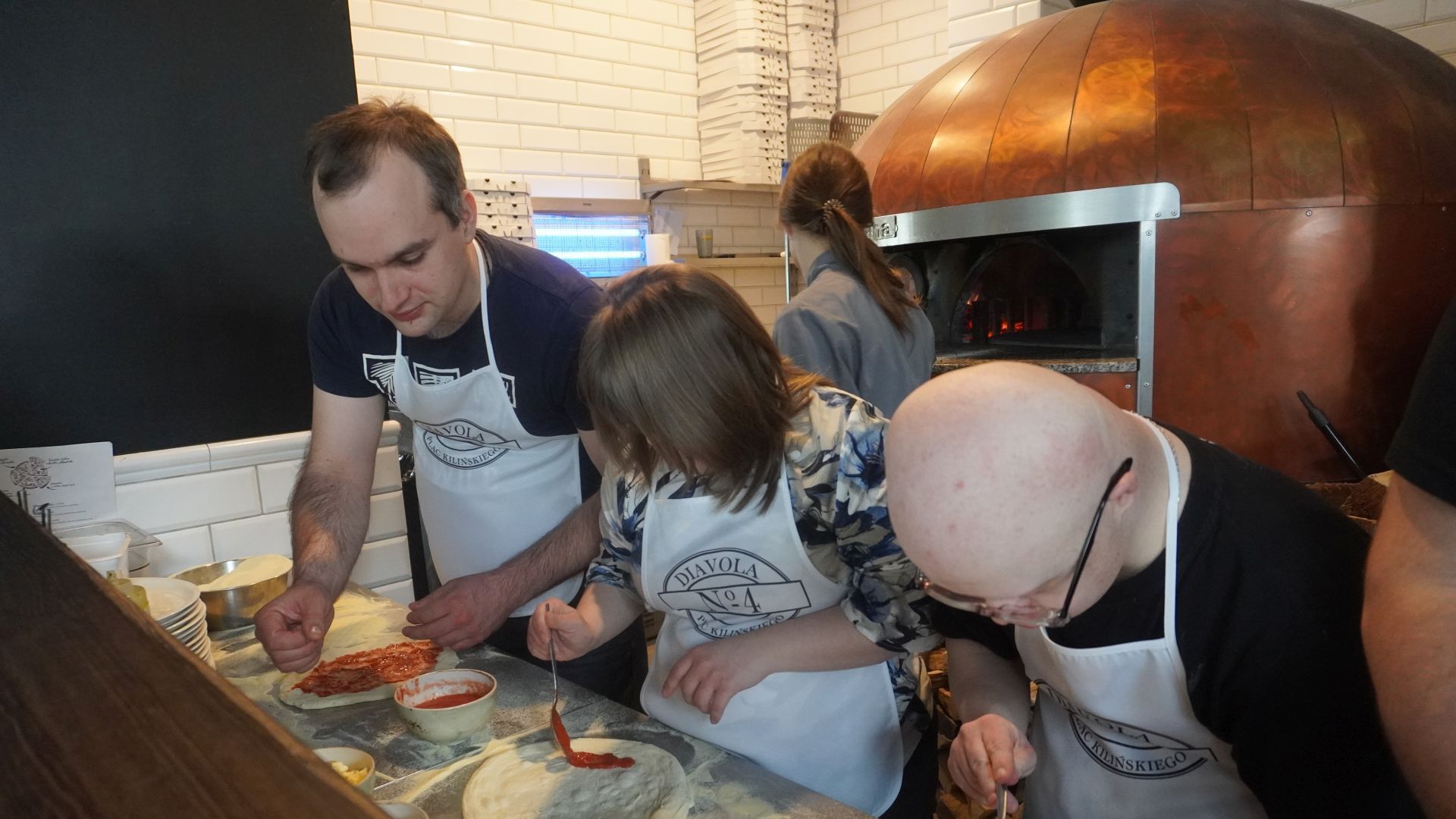 Uczestnicy przygotowują swoje pizze podczas warsztatów w pizzerii Diavola. 
