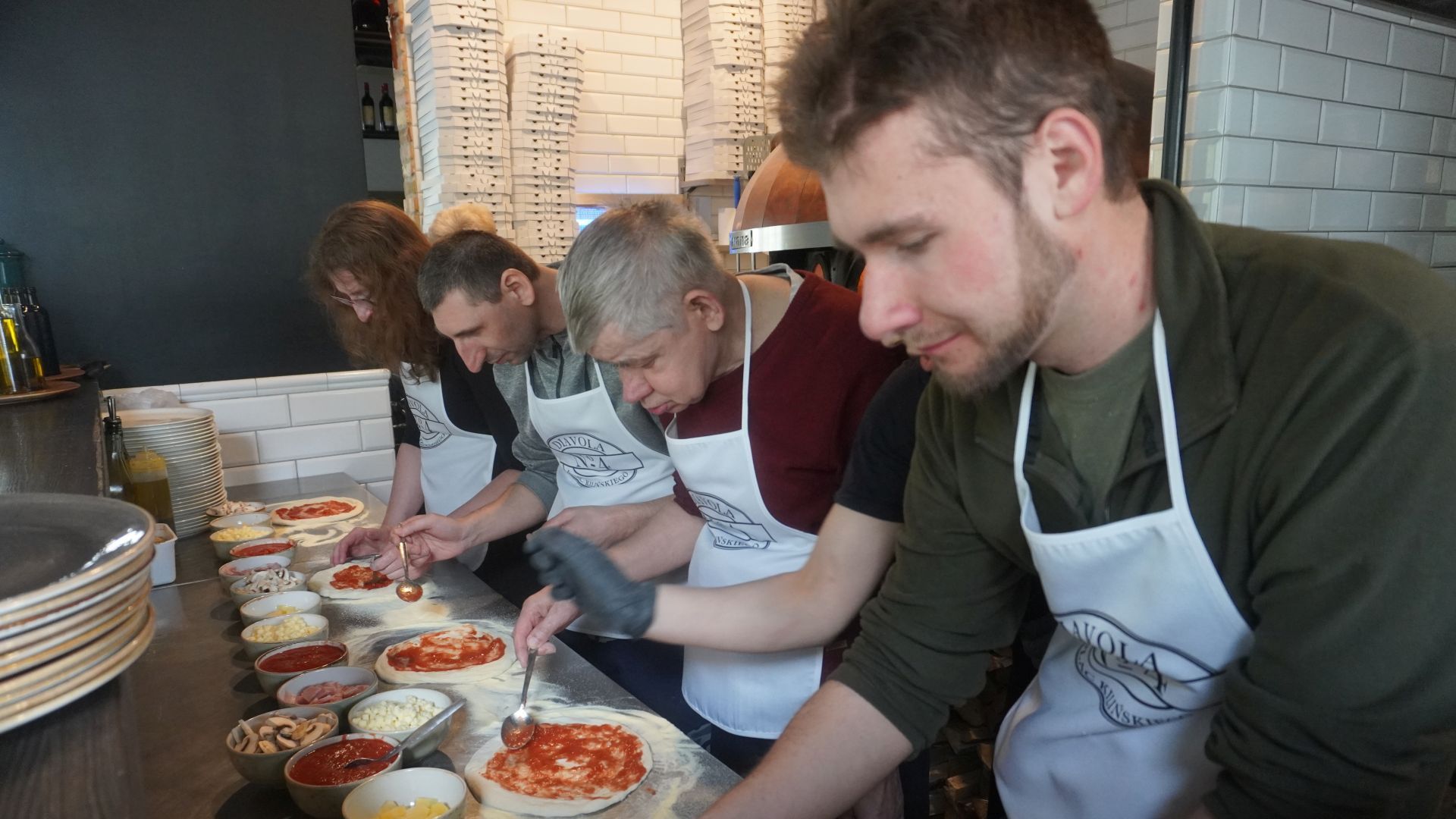 Uczestnicy przygotowują swoje pizze podczas warsztatów w pizzerii Diavola. 