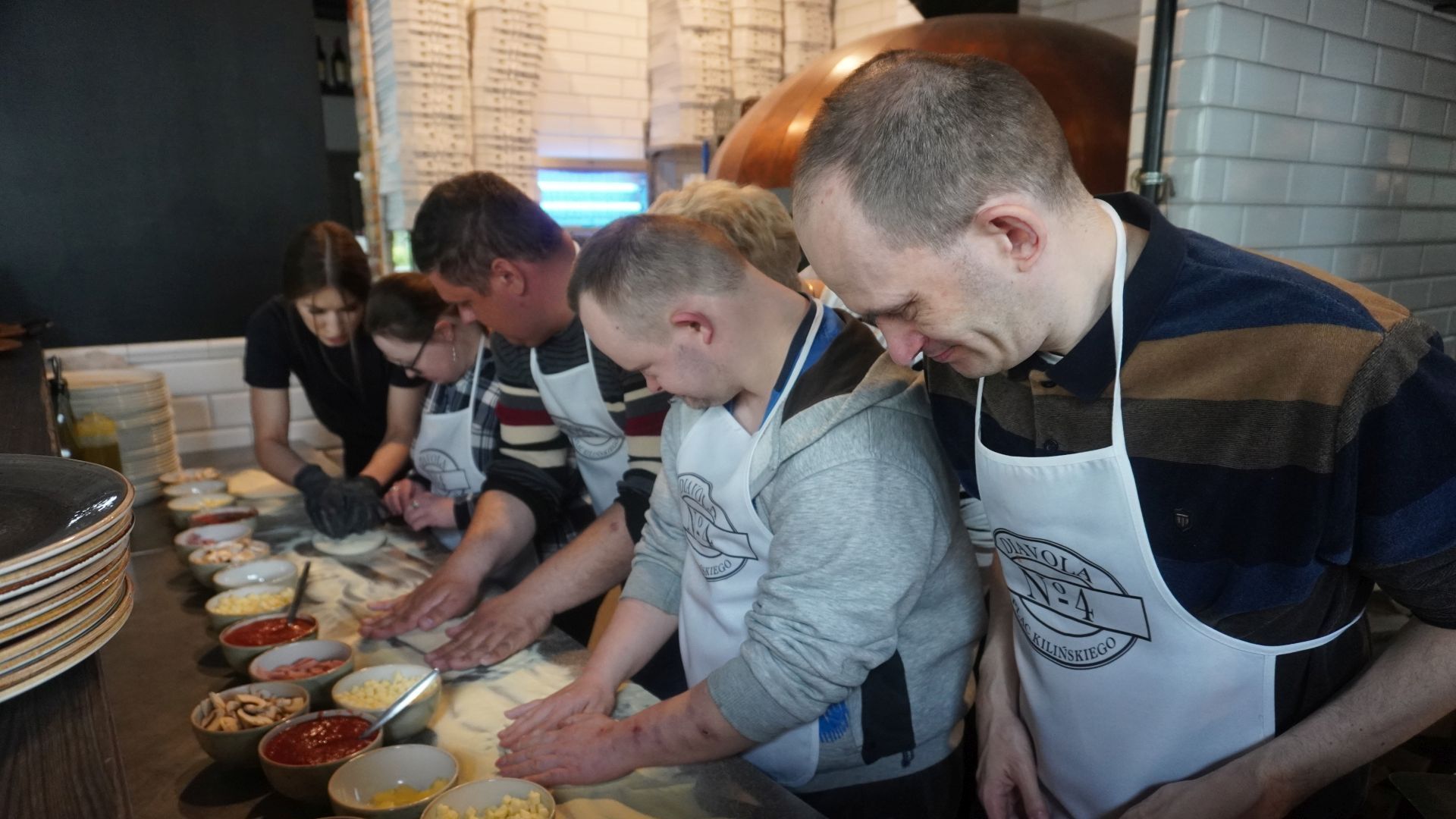 Uczestnicy przygotowują swoje pizze podczas warsztatów w pizzerii Diavola. 