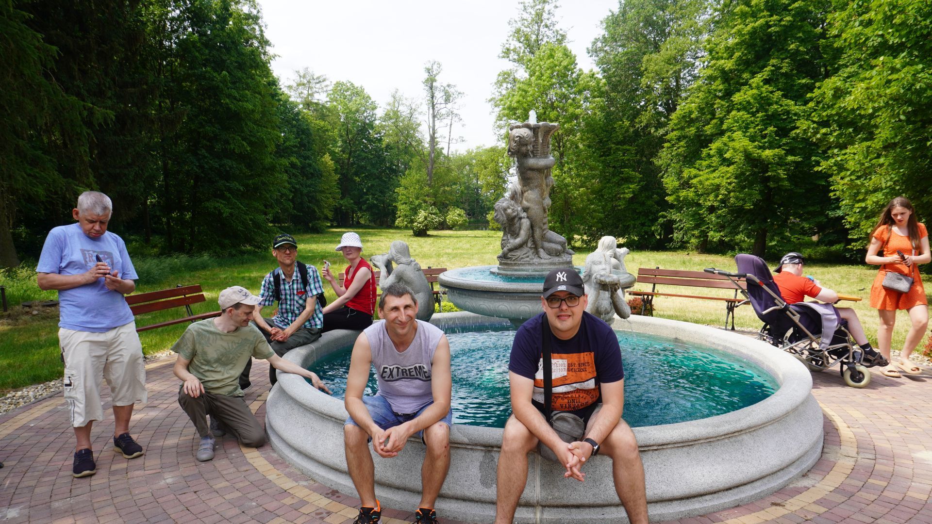 Uczestnicy pozują do zdjęcia przy fontannie podczas Pikniku Rodzinnego ''Całkiem nowa bajka'' w DPS w Kątach.