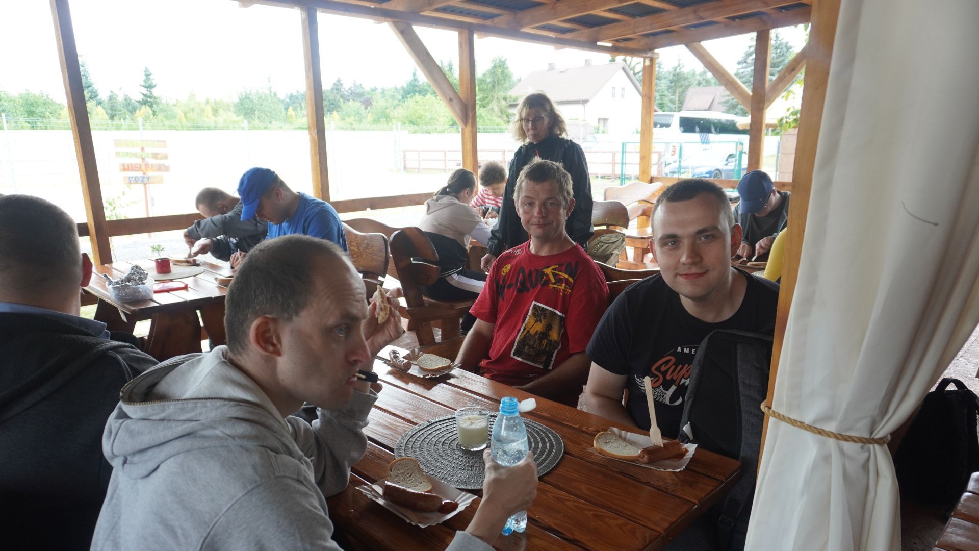 Uczestnicy jedzą kiełbaski z ogniska podczas odpoczynku na ''Farmie Goławice''.