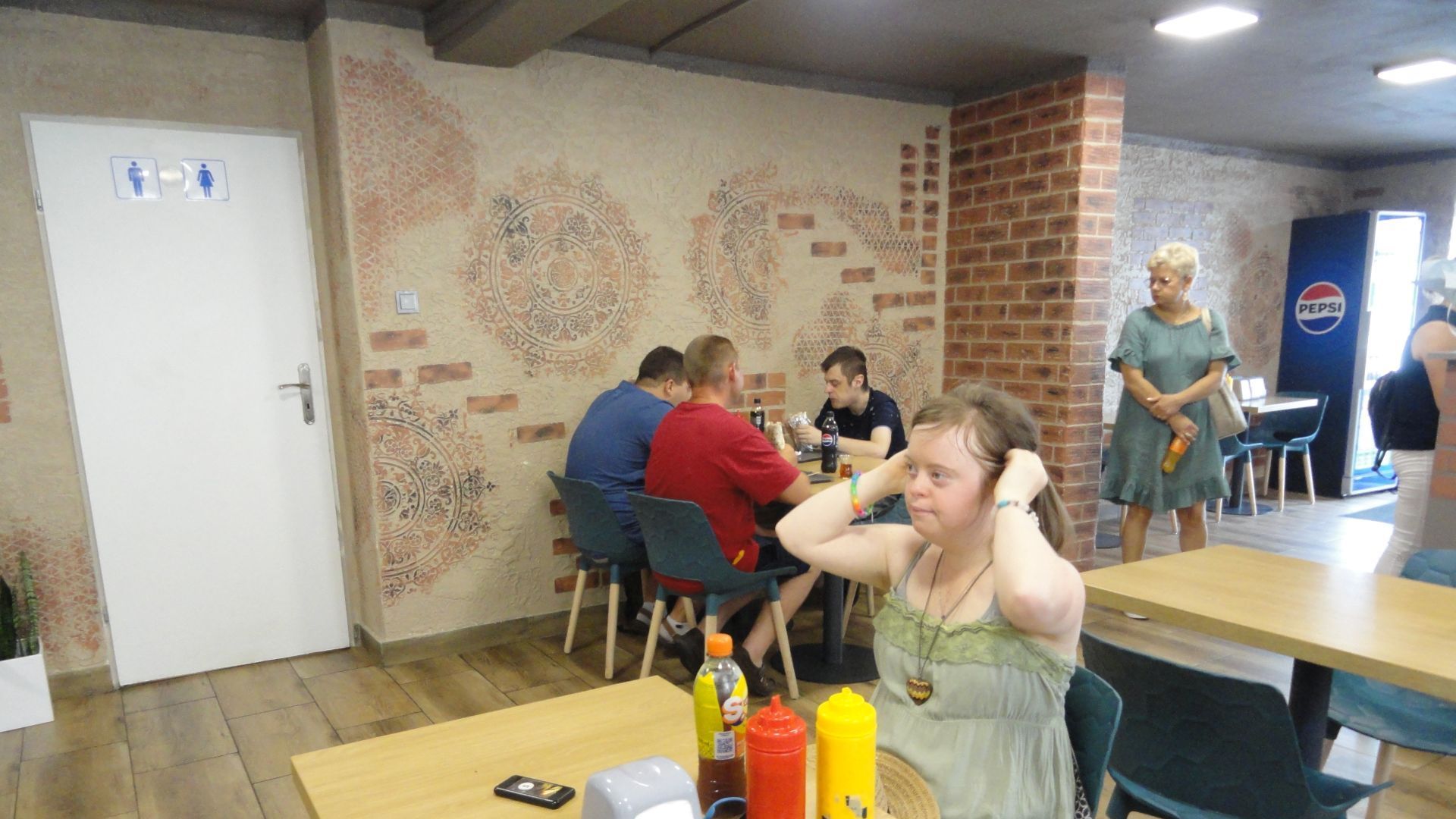 Uczestnicy siedzą przy stolikach w restauracji i czekają na kebaby.