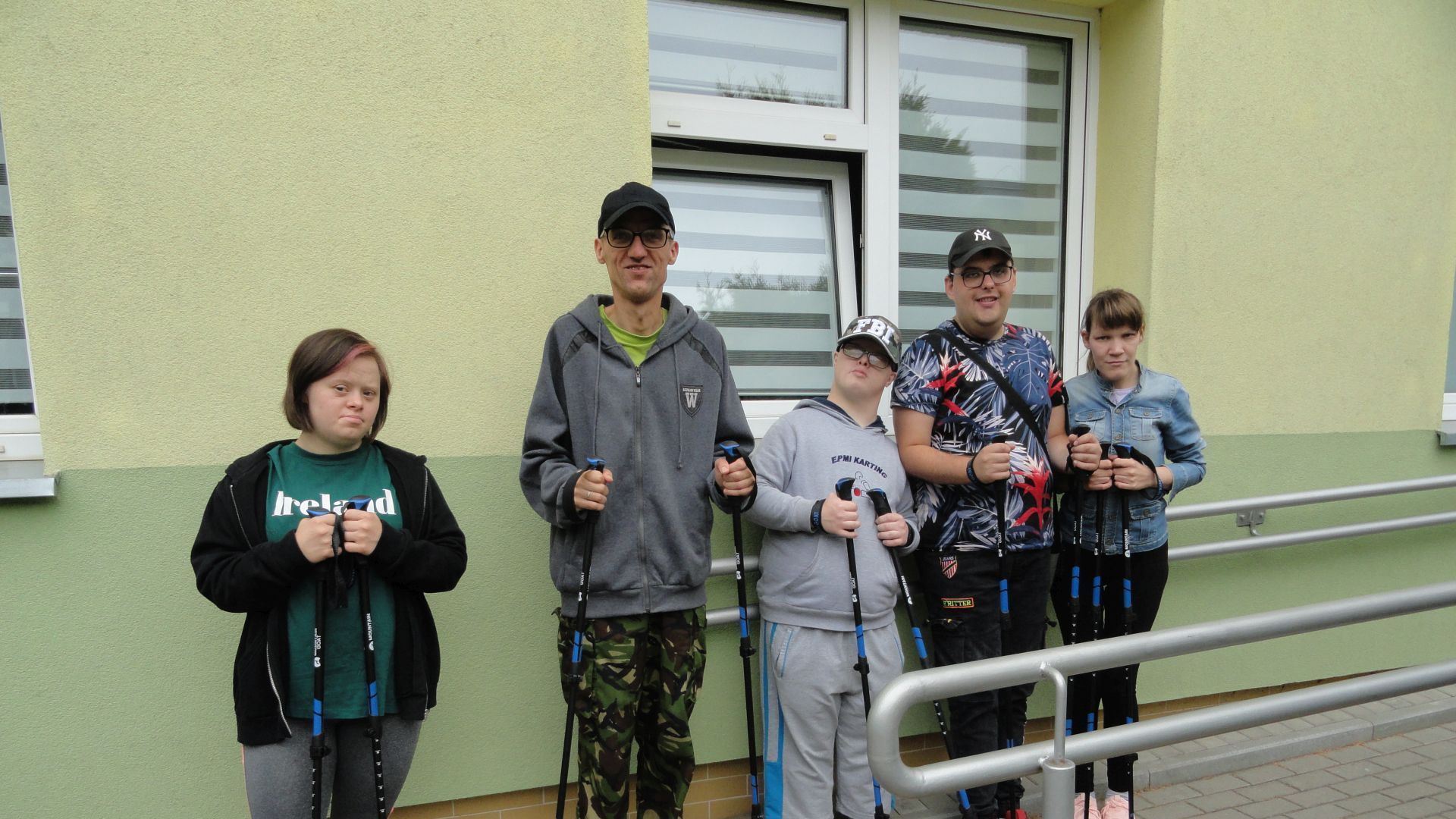 Uczestnicy stoją przed budynkiem PŚDS z kijkami do nordic walking.