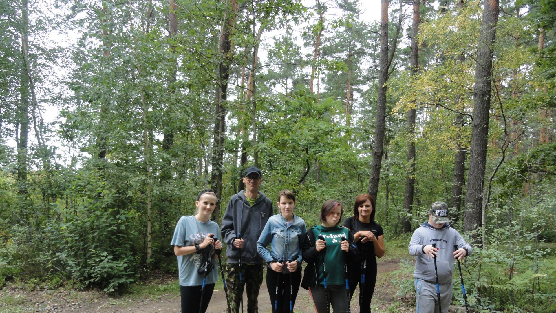 Uczestnicy wraz z terapeutami odpoczywają podczas marszu nordic walking. 