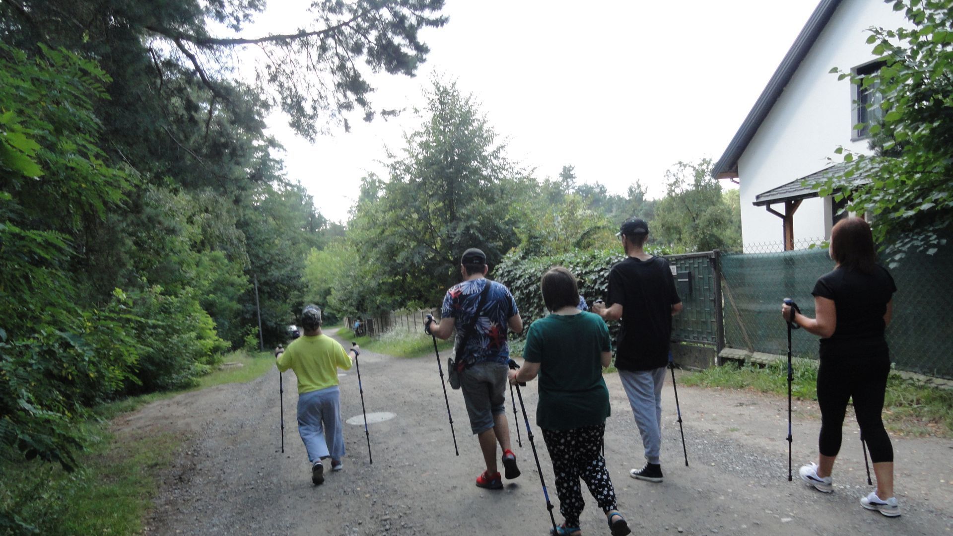 Uczestnicy wraz z terapeutą maszerują z kijkami nordic walking.