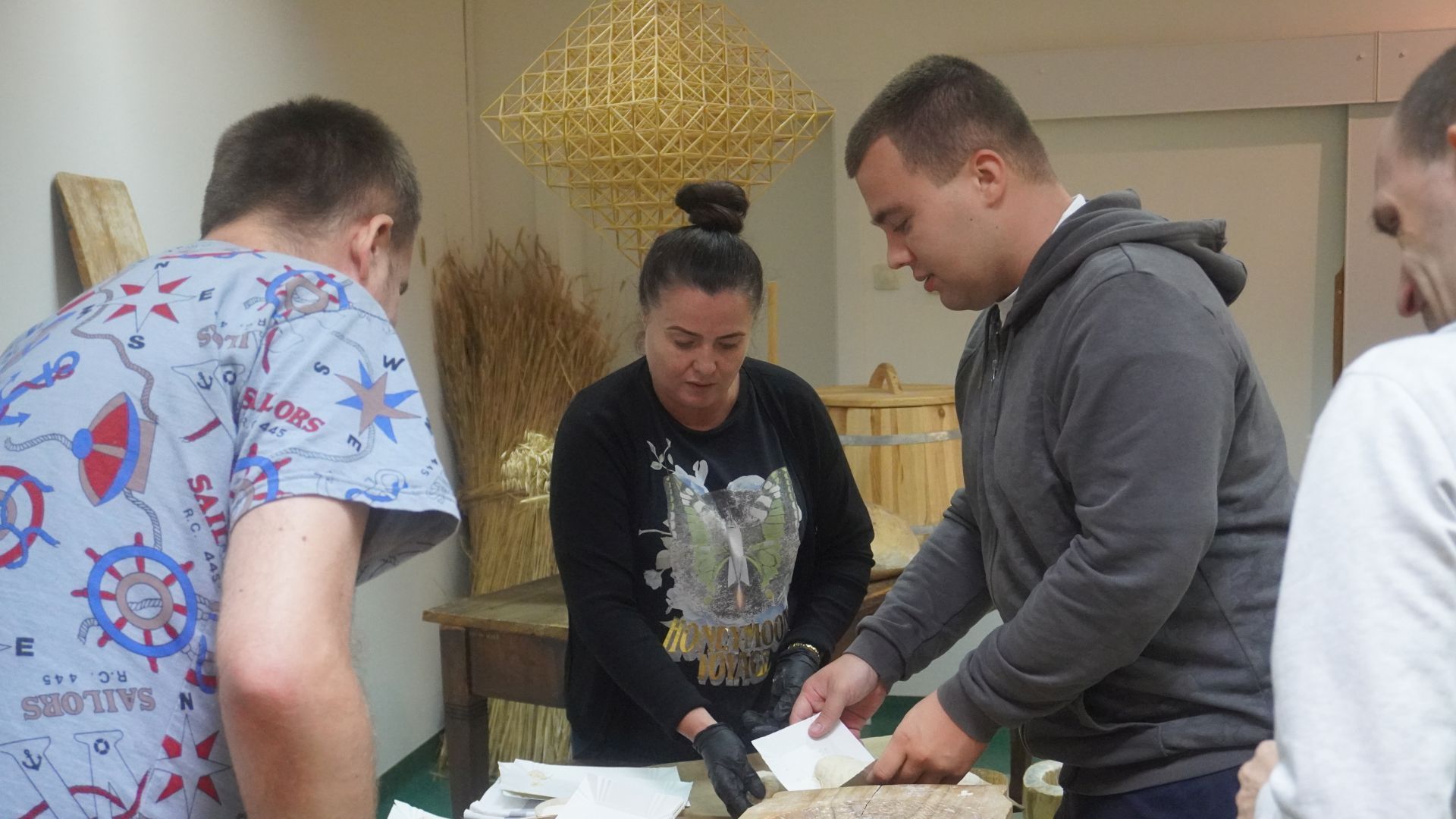 Uczestnicy układają na blaszkę przygotowane przez siebie bułki podczas warsztatów ''Od ziarenka do bochenka'' w Muzeum Wsi Radomskiej.