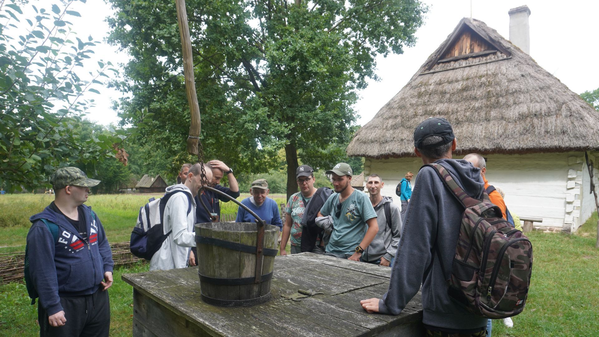 Uczestnicy przy starej studni podczas zwiedzania Muzeum Wsi Radomskiej.