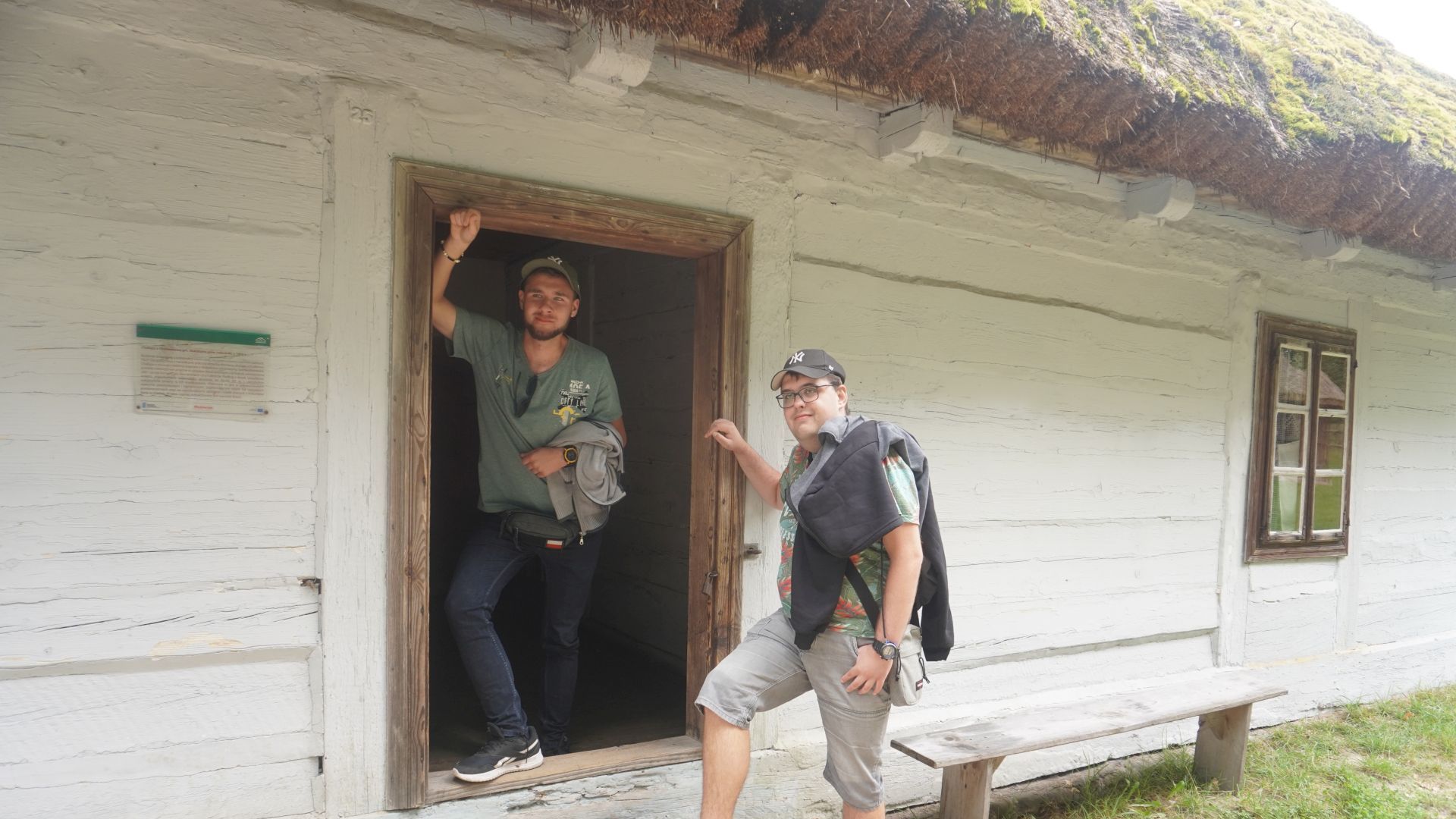 Uczestnicy Bartek i Karol pozują na tle starej chaty w Muzeum Wsi Radomskiej. 