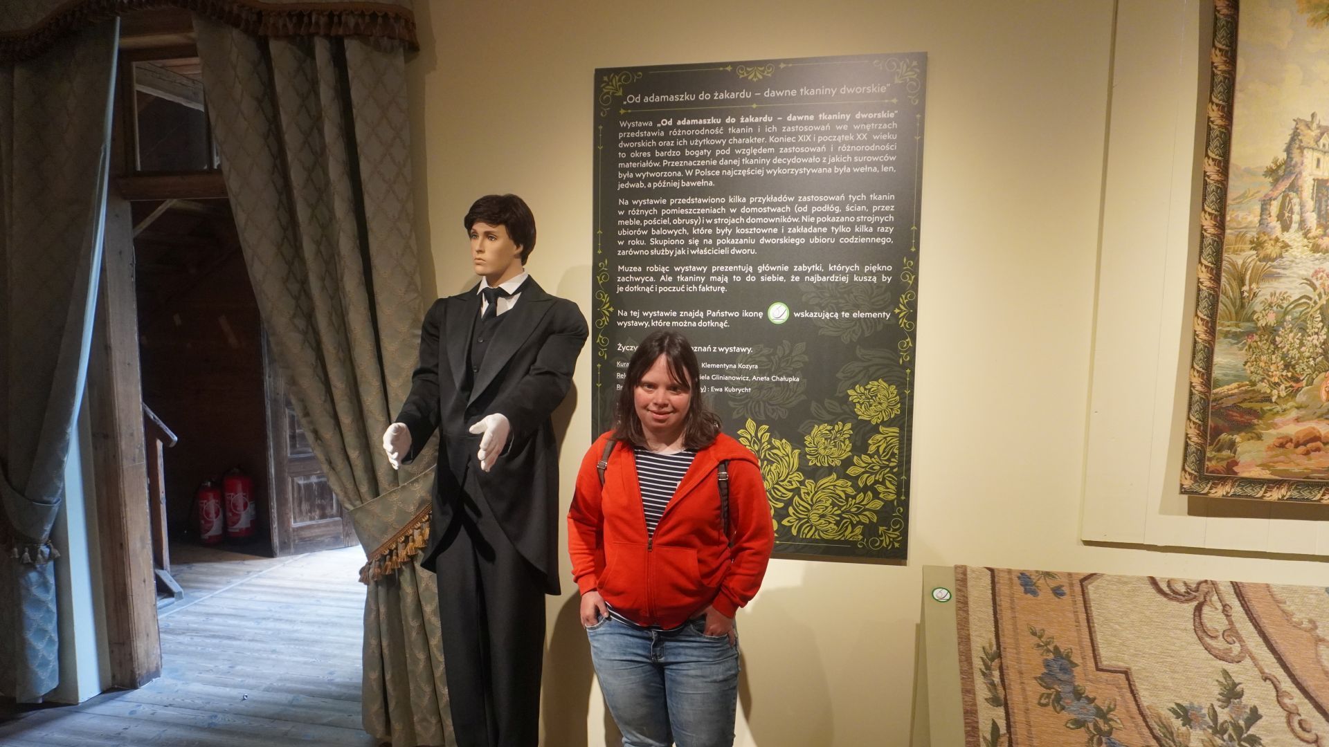 Uczestniczka Justyna w Muzeum Wsi Radomskiej stoi obok manekina ubranego w smoking.