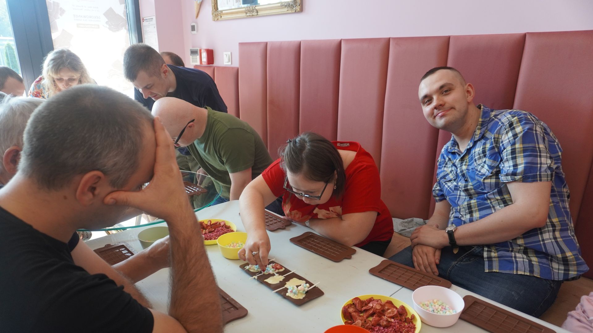 Uczestnicy podczas warsztatów dekorowania czekolady ozdabiają czekoladowe lizaki.