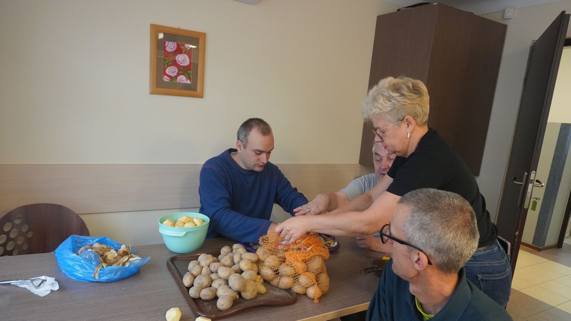 Uczestnicy podczas przygotowań do grilla z okazji Dnia Pieczonego Ziemniaka w pracowni kulinarnej obierają ziemniaki. 