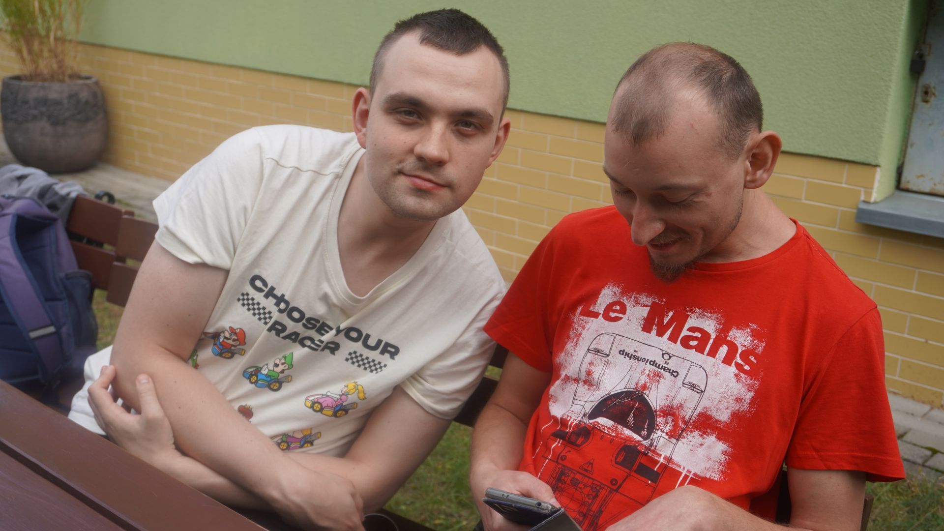 Uczestnicy siedzą za stołem podczas grilla w ogrodzie z okazji Dnia Pieczonego Ziemniaka. 