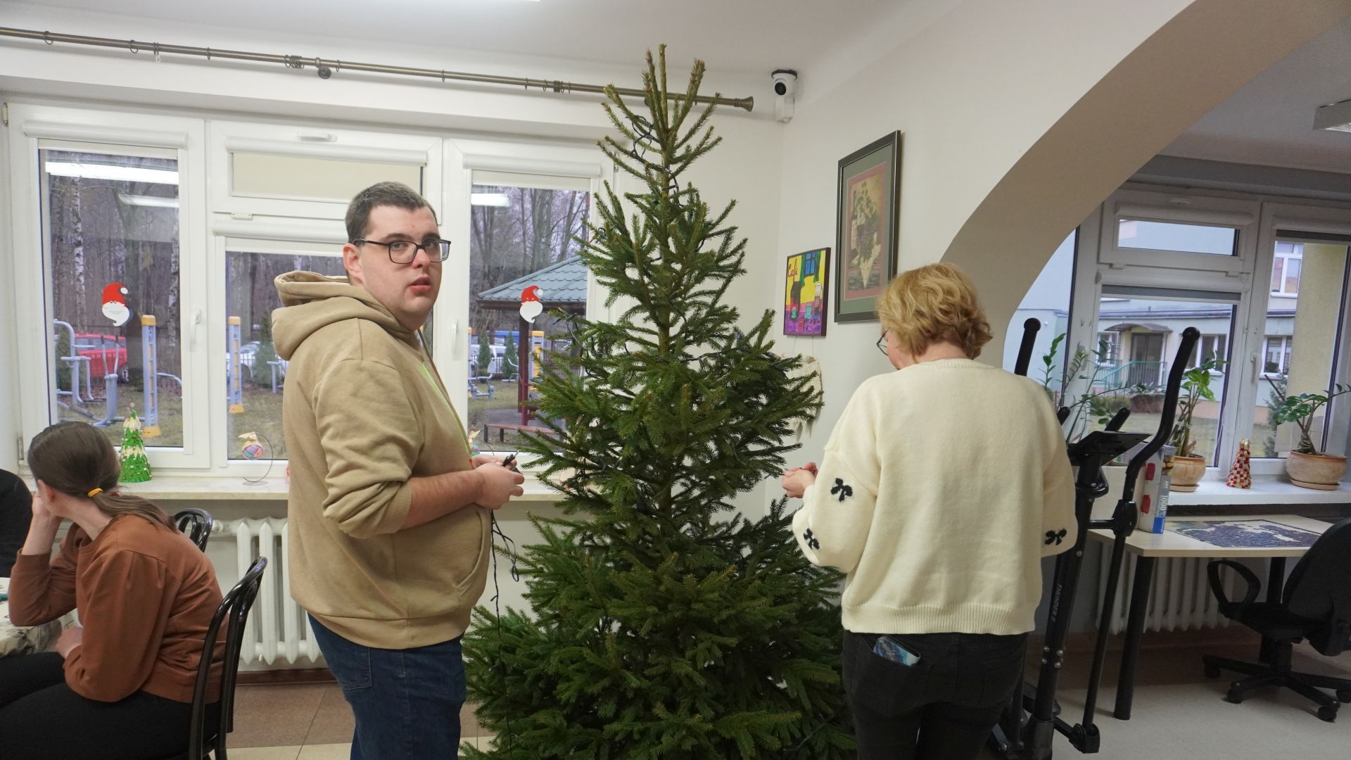 Uczestnik Karol i Pani Marta wspólnie zawieszają lampki na choince. 