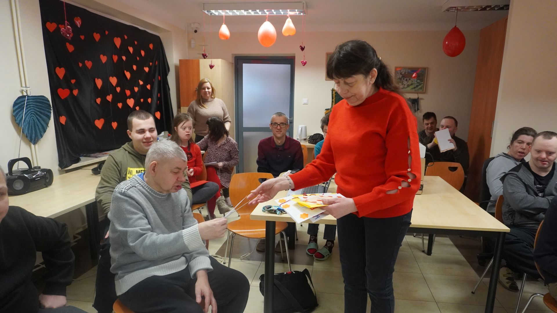 Pani Małgosia przekazuje uczestnikowi kartkę walentynkową z poczty walentynkowej. 