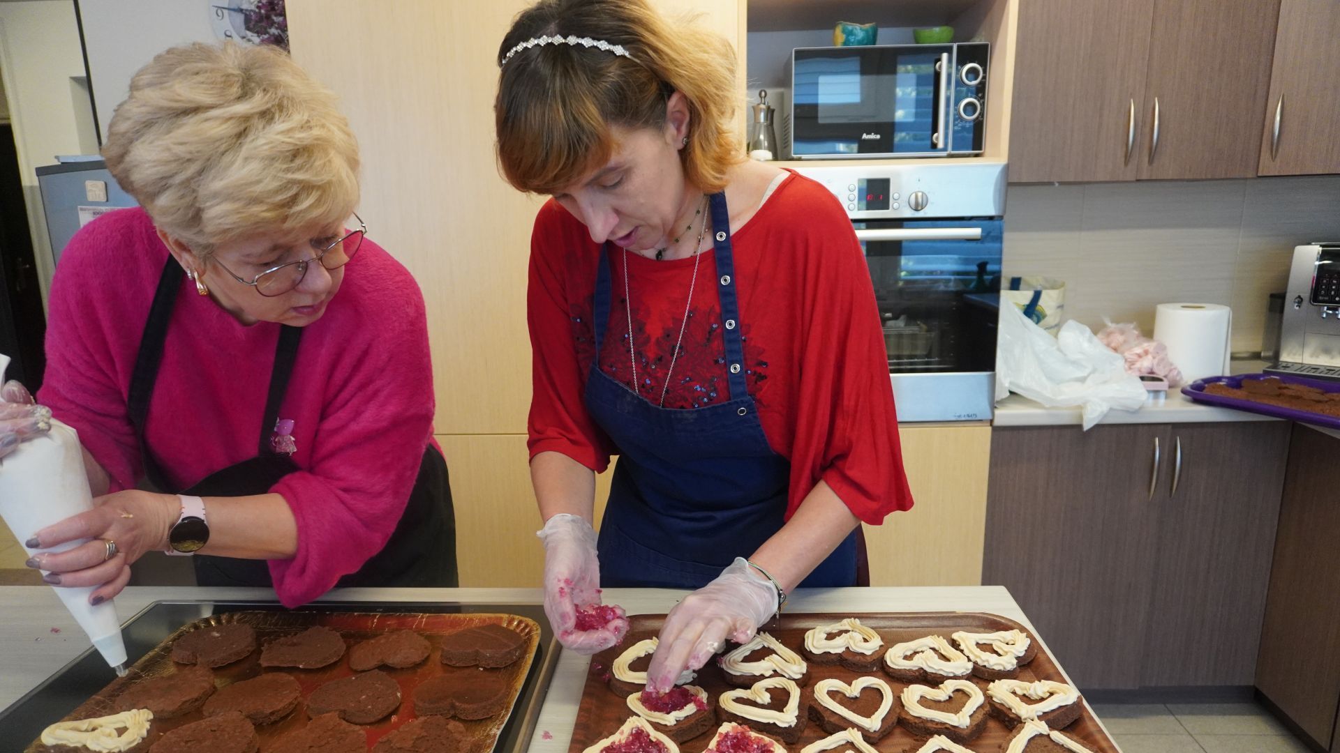 Pani Iwona i uczestniczka Agnieszka W. dekorują ciastka walentynkowe.