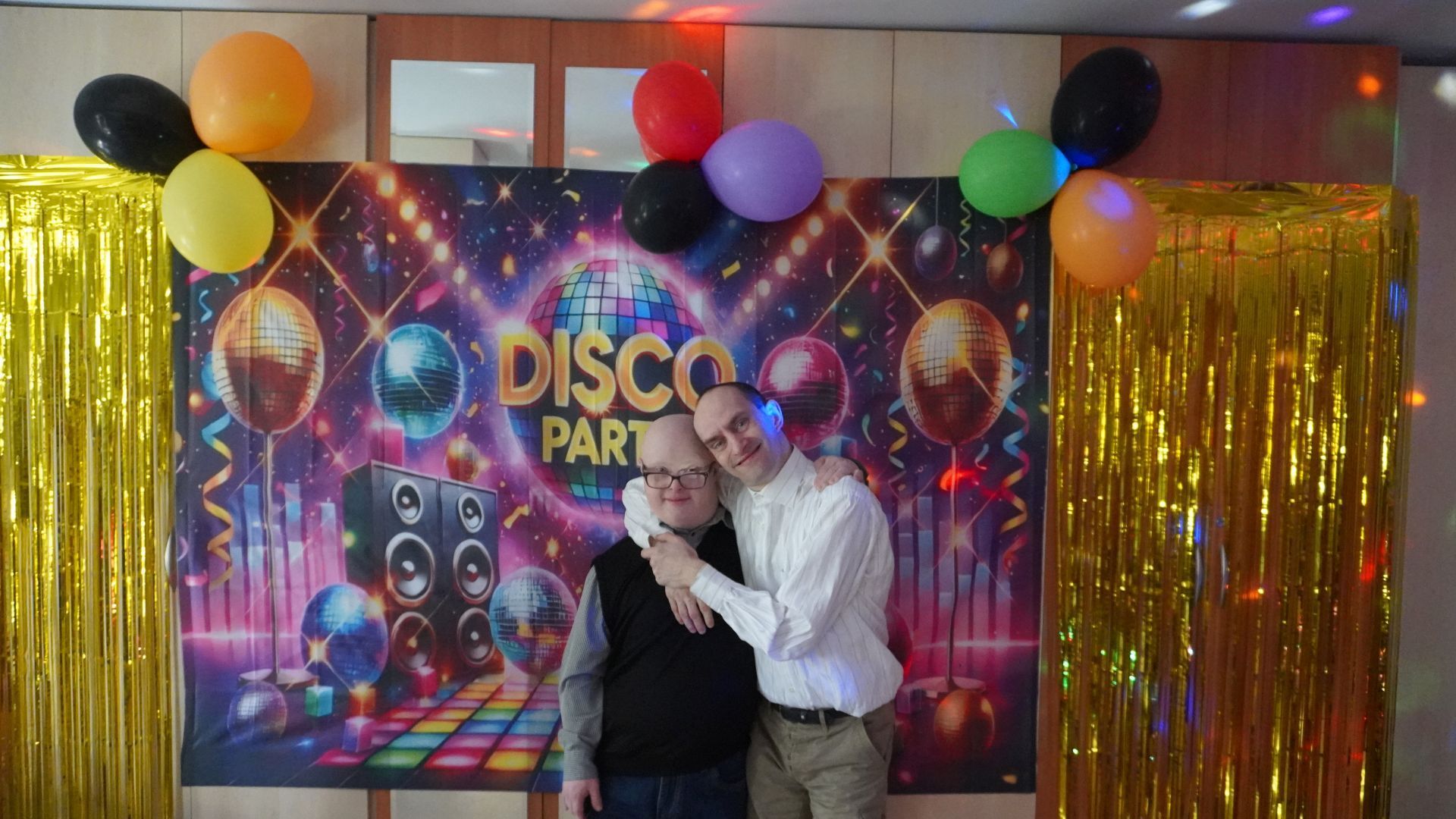 Uczestnicy Mateusz i Paweł pozują do zdjęcia na ściance z napisem Disco Party.