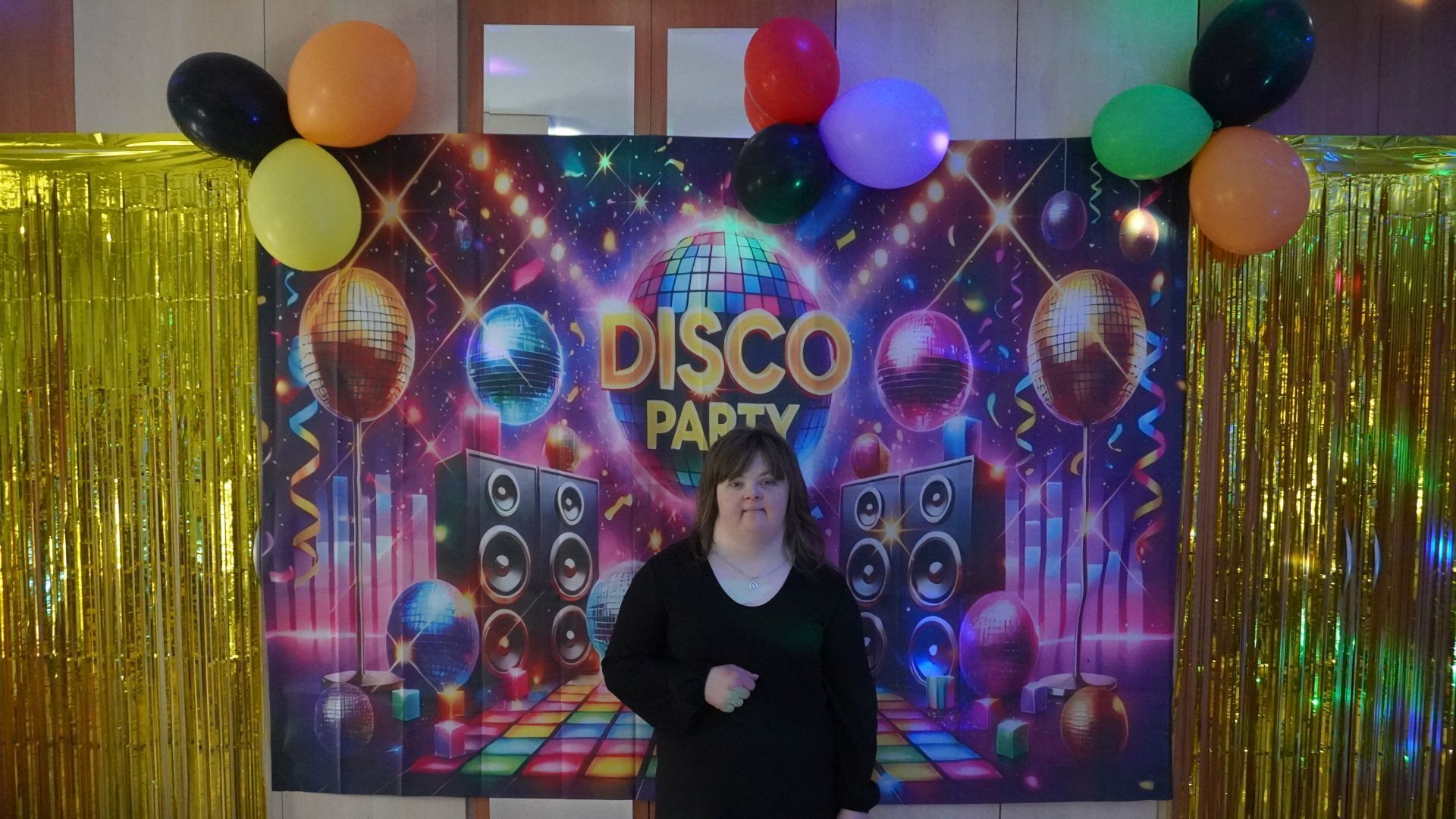 Uczestniczka Sylwia pozuje do zdjęcia na ściance z napisem Disco Party.