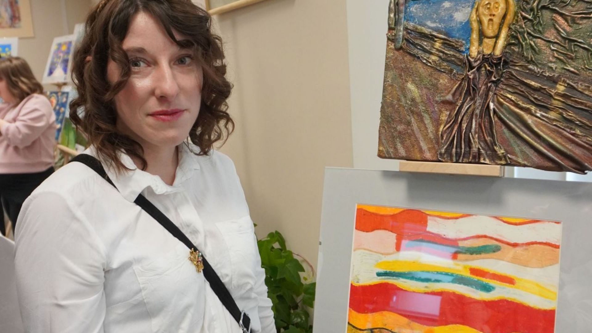 Justyna K. pozuje do zdjęcia na tle wykonanych przez siebie prac podczas wernisażu ''Sztuka-moja pasja''. 