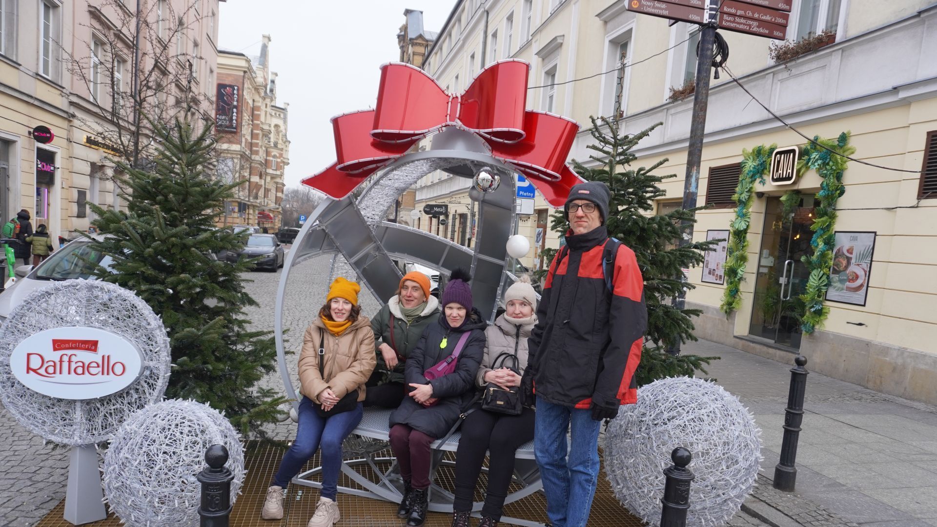 Uczestnicy pozują do grupowego zdjęcia podczas spaceru po słynnej ulicy Nowy Świat w Warszawie.