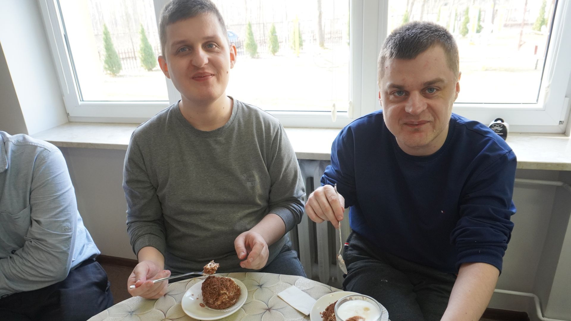 Uczestnicy Łukasz i Damian jedzą ciastka podczas Dnia Kobiet i Mężczyzn.