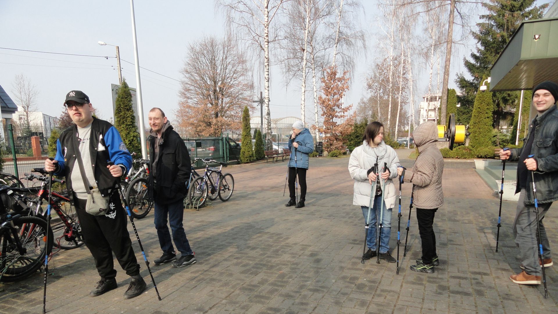 Uczestnicy pozują z kijkami podczas zajęć nordic walking. 