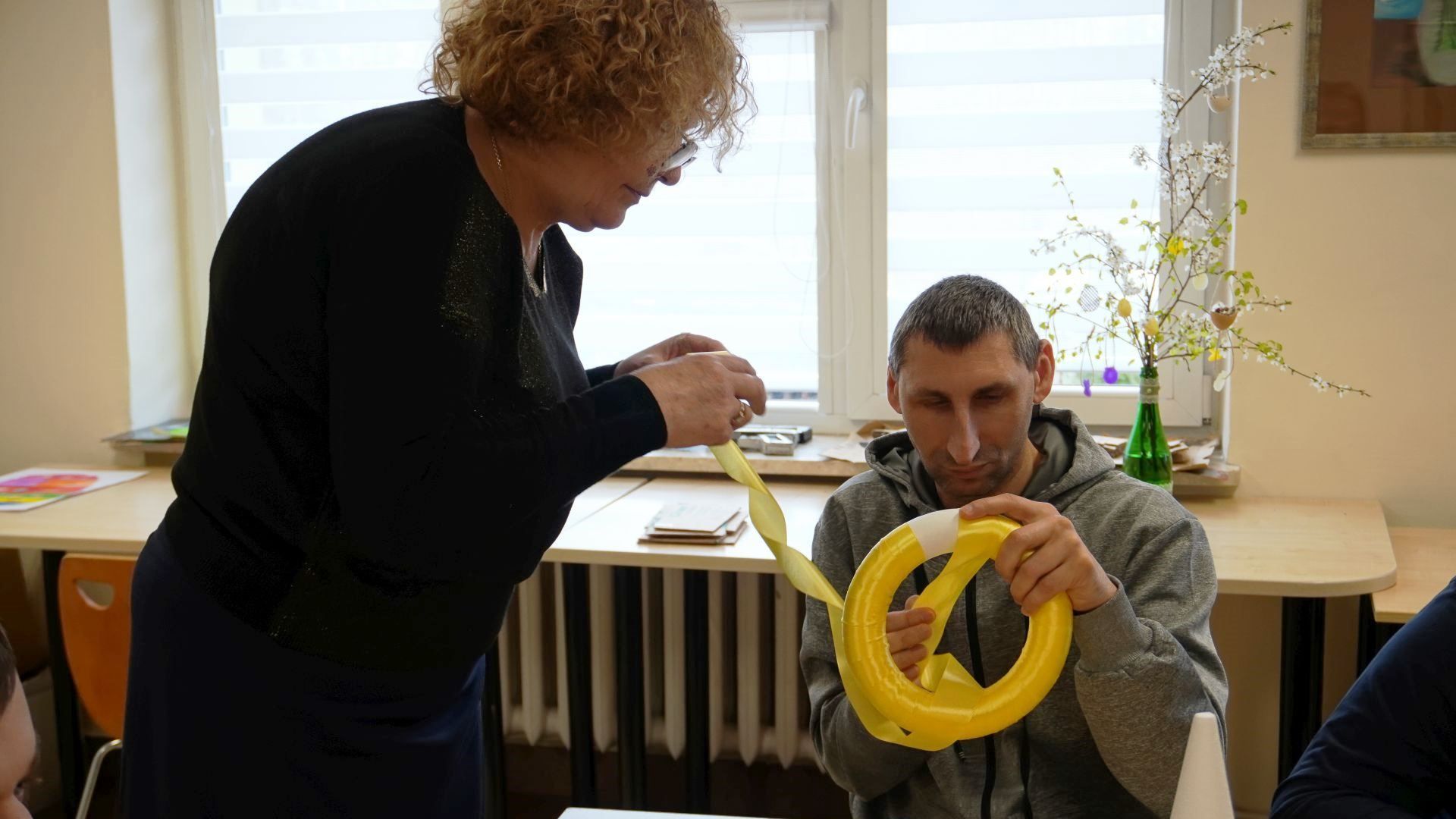 Uczestnik Sebastian wykonuje wianek wielkanocny z pomocą pani praktykantki.