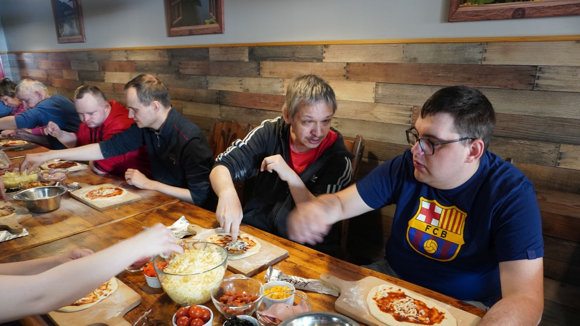 Uczestnicy przygotowują swoje pizze podczas Warsztatów Wypieku Pizzy.