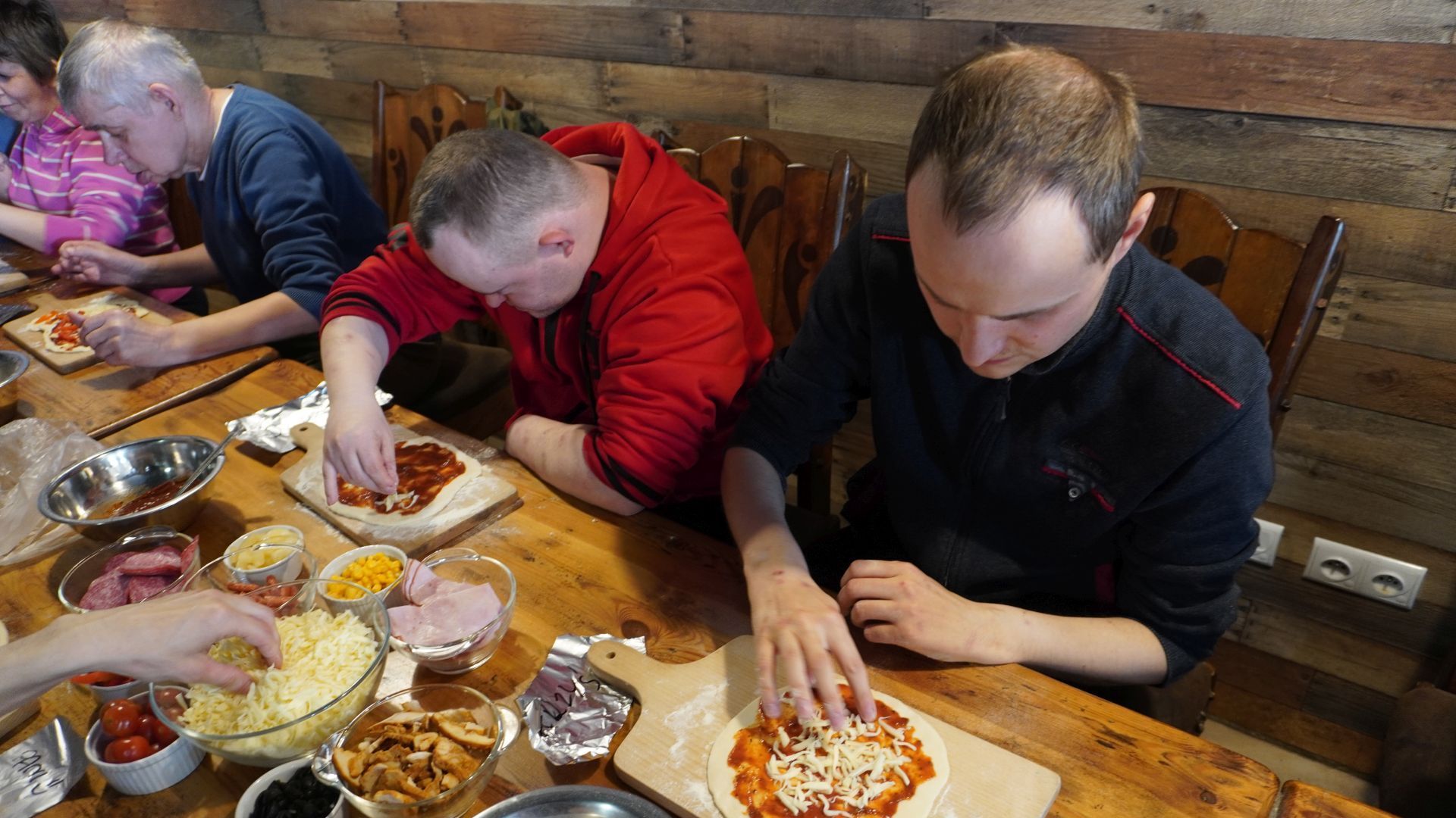 Uczestnicy przygotowują swoje pizze podczas Warsztatów Wypieku Pizzy.