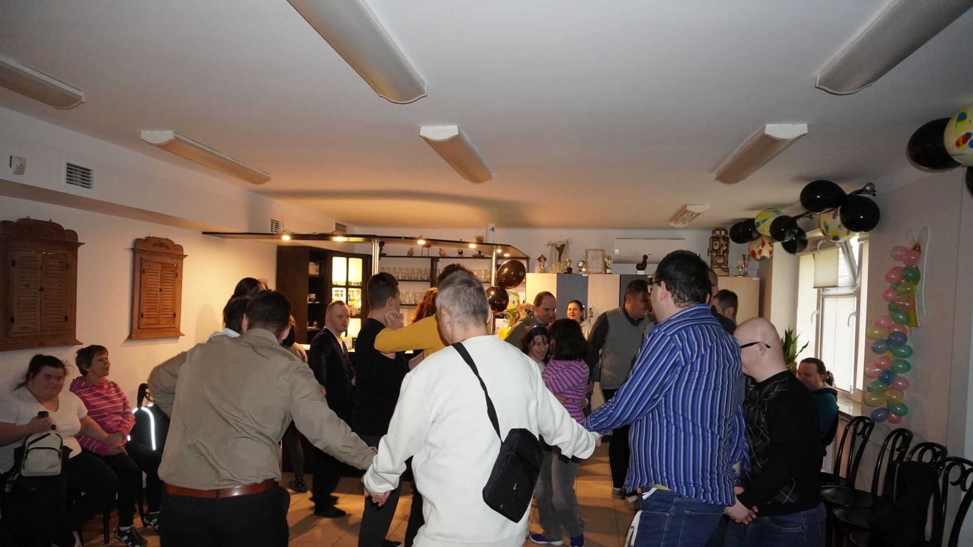 Uczestnik naszego Domu tańczą w kółku podczas imprezy andrzejkowej 2025.