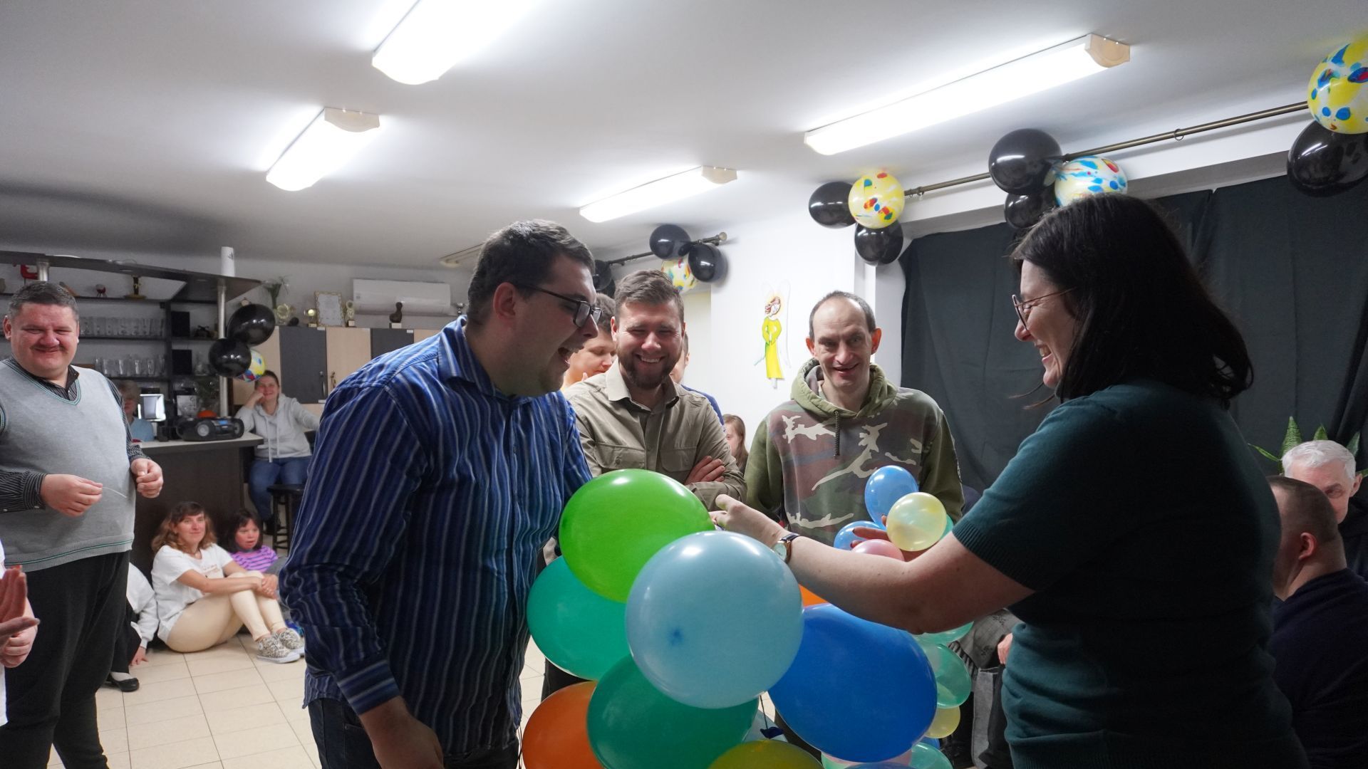 Uczestnik naszego Domu Karol przebija balon z wróżbą podczas imprezy andrzejkowej.