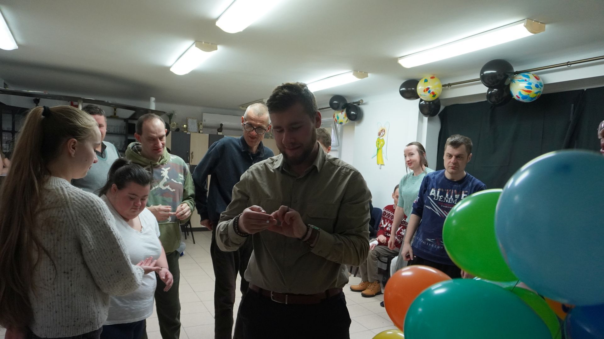 Uczestnik naszego Domu Bartek czyta karteczkę z wróżbą podczas imprezy andrzejkowej 2025.