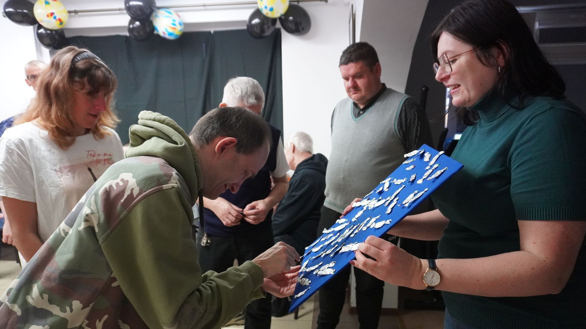 Uczestnik naszego Domu Paweł W. wybiera wróżbę podczas imprezy andrzejkowej 2025.