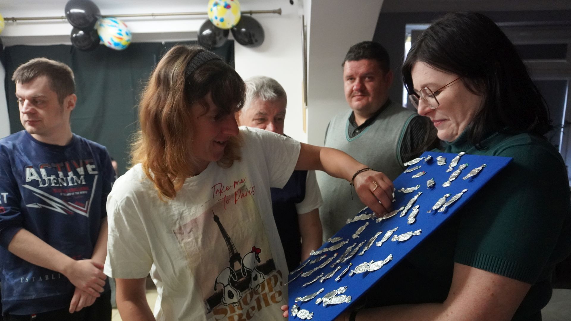 Uczestniczka naszego Domu Agnieszka W. wybiera wróżbę podczas imprezy andrzejkowej 2025.