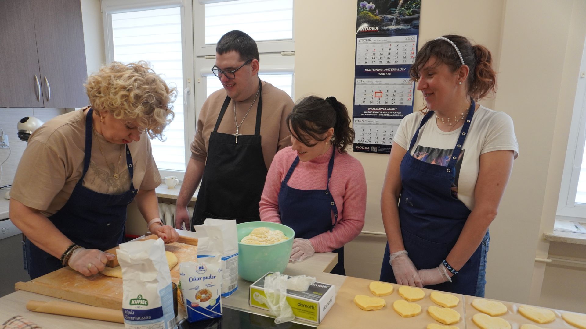 Uczestnicy wraz z terapeutą zajęciowym w pracowni kulinarnej przygotowują pączki na Tłusty Czwartek.