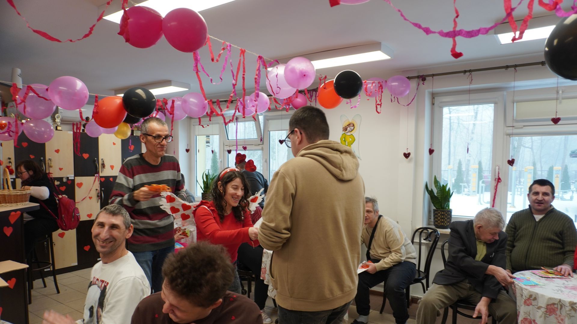 Przewodniczący Rady Domu wręczają kartki walentynkowe uczestnikowi Karolowi.