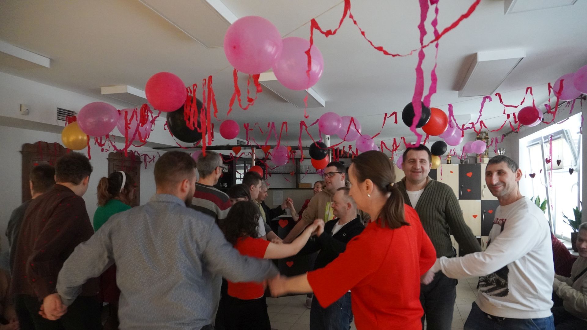 Uczestnicy tańczą razem w kółku podczas dyskoteki walentynkowej. 