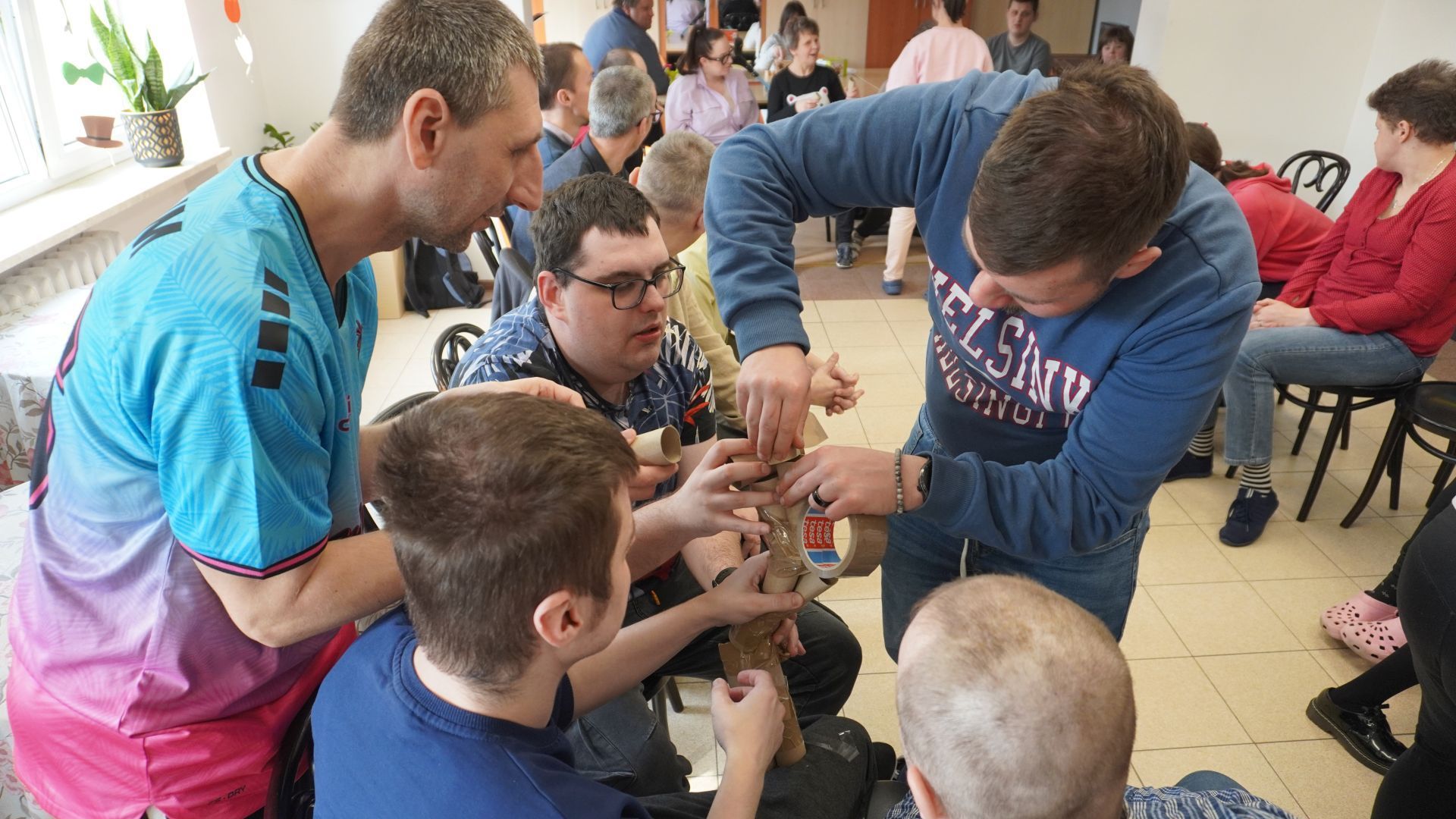 Uczestnicy sklejają wieżę z rolek po papierze toaletowym podczas zajęć integracyjnych z okazji Dnia Kobiet i Mężczyzn.