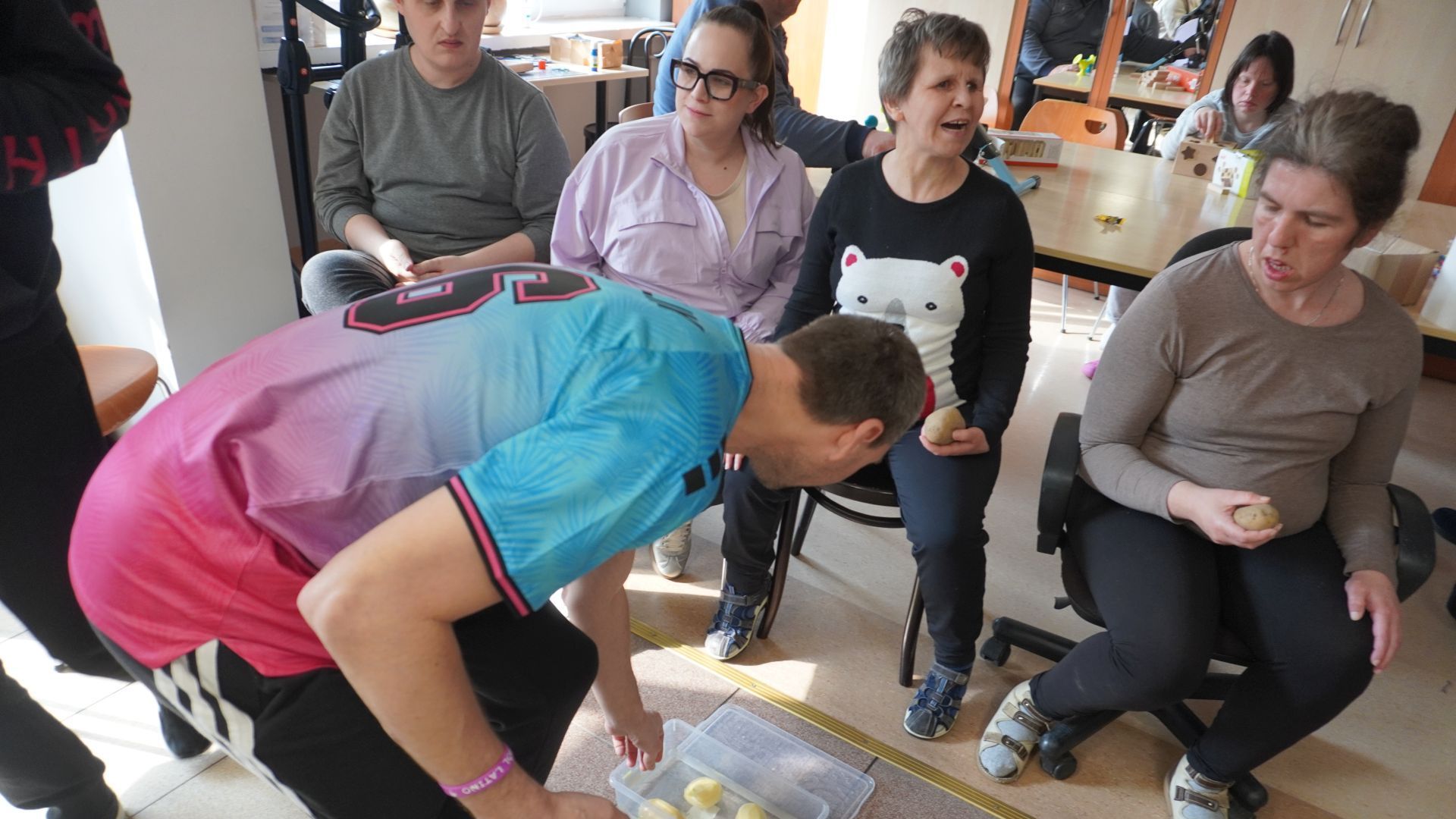 Uczestnik Sebastian wrzuca obranego ziemniaka do pojemnika z wodą podczas zajęć integracyjnych z okazji Dnia Kobiet i Mężczyzn. 