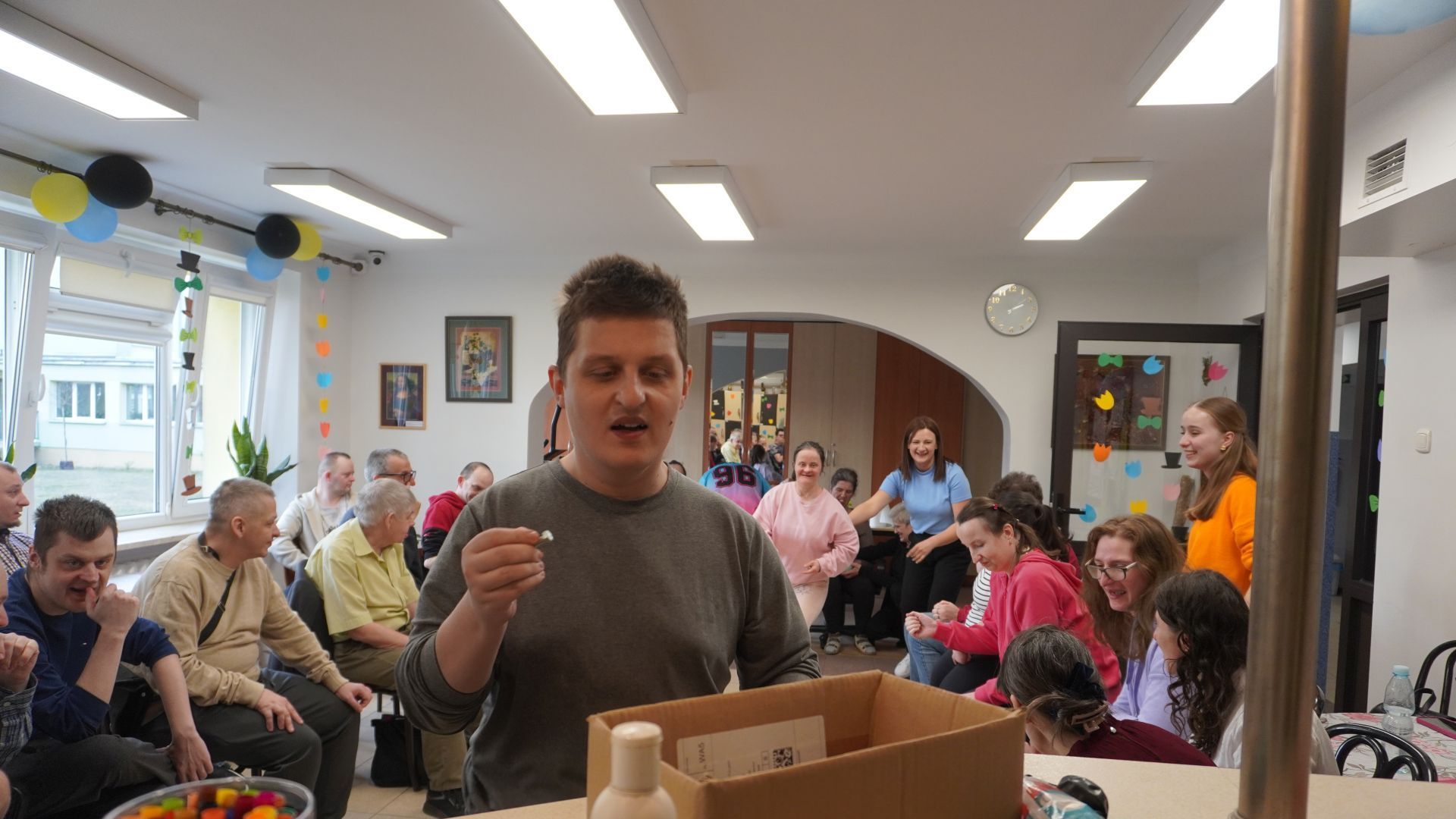 Uczestnik Damian S. wrzuca śrubki do pudełka podczas zajęć integracyjnych z okazji Dnia Kobiet i Mężczyzn. 