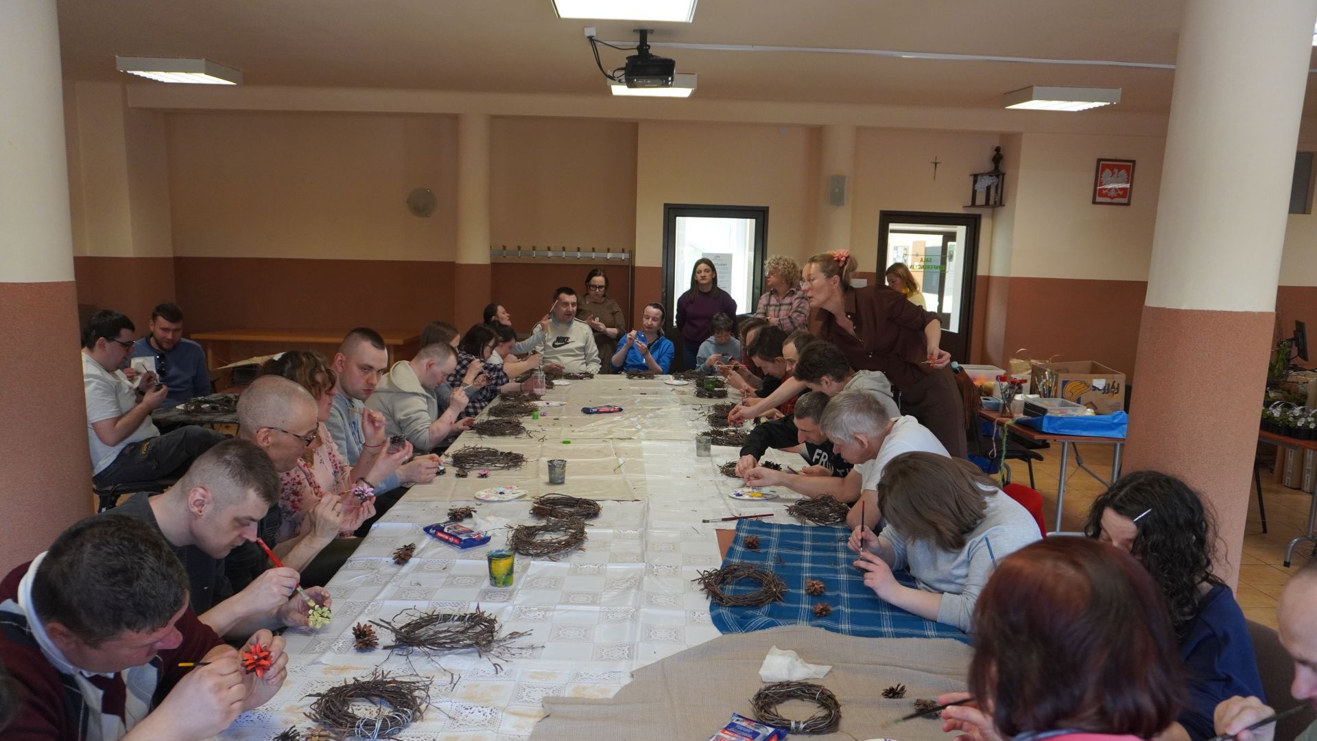 Uczestnicy malują szyszki podczas wielkanocnych warsztatów artystycznych.